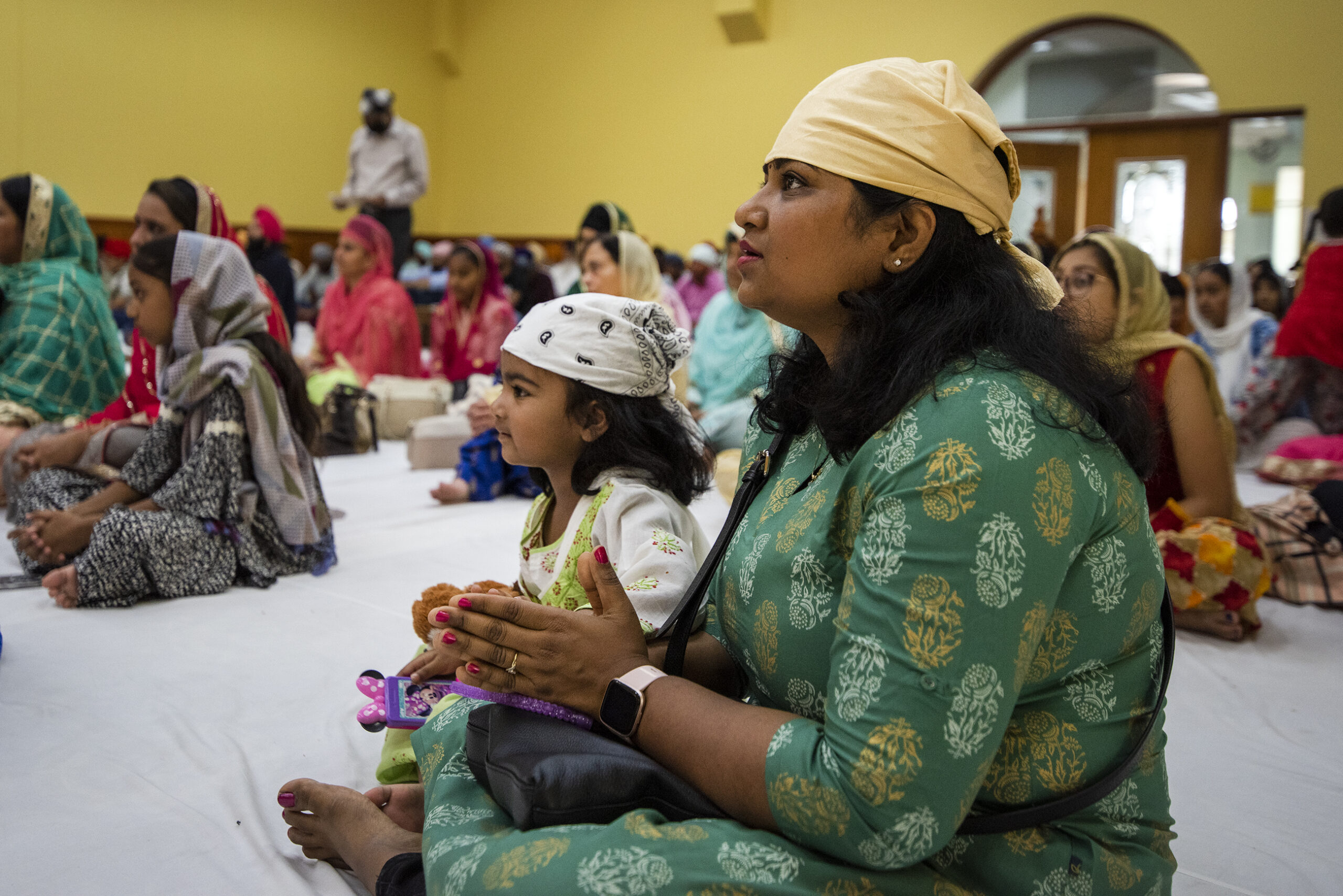 A woman sits on the ground with other members during service.