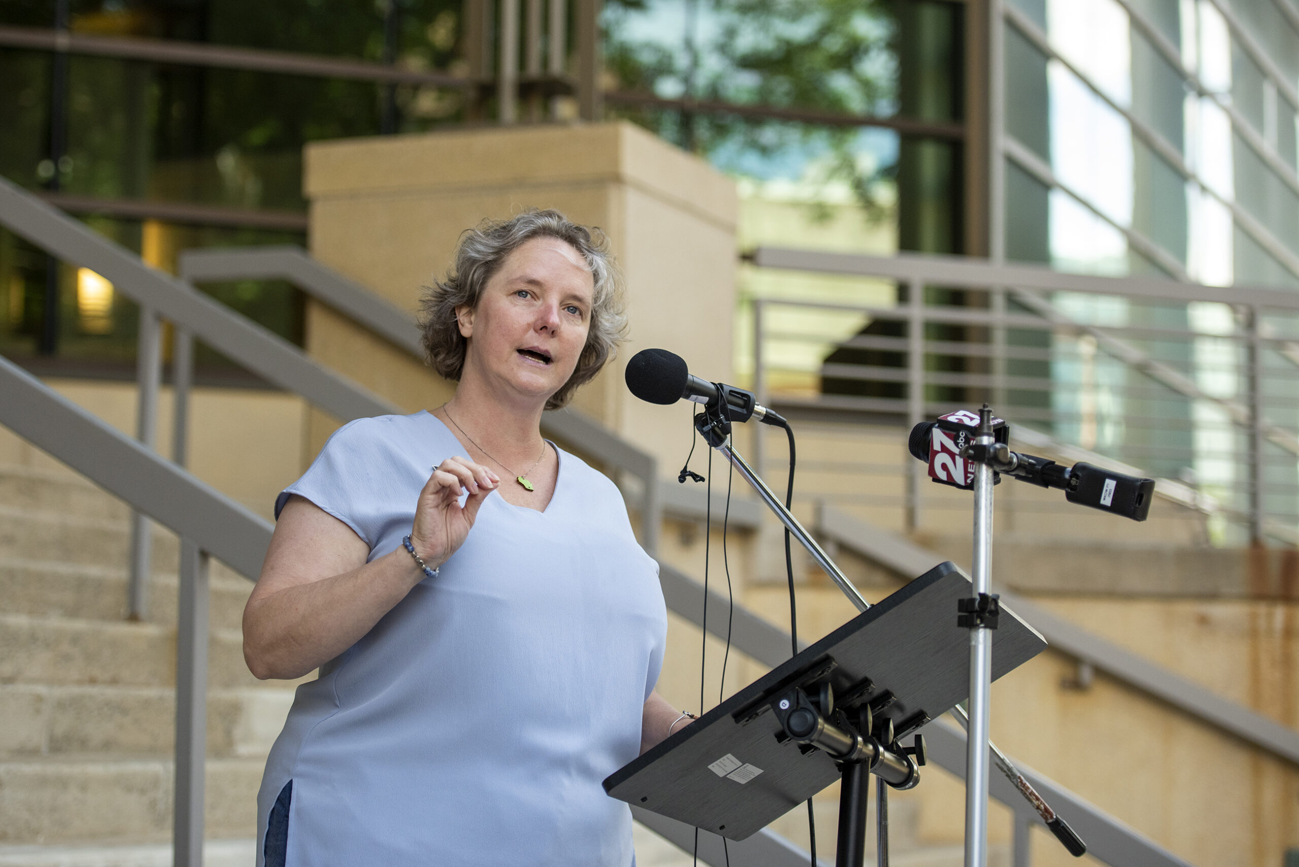 Satya Rhodes-Conway stands outside near steps to the courthouse as she speaks at a podium.