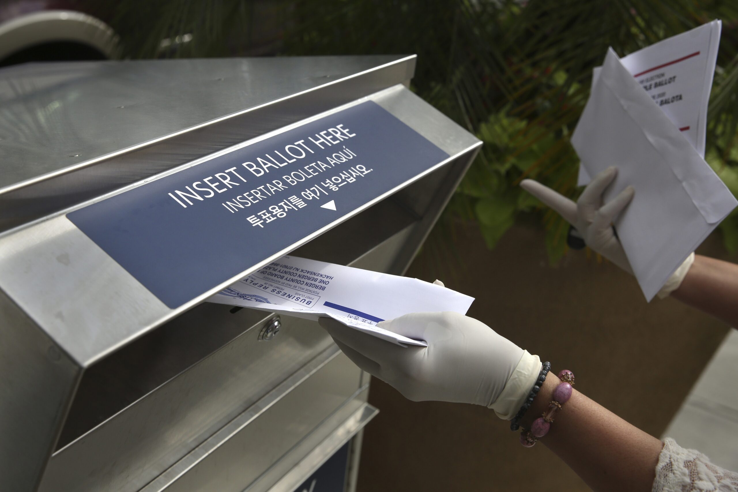 A woman drops off a mail-in ballot at a drop box