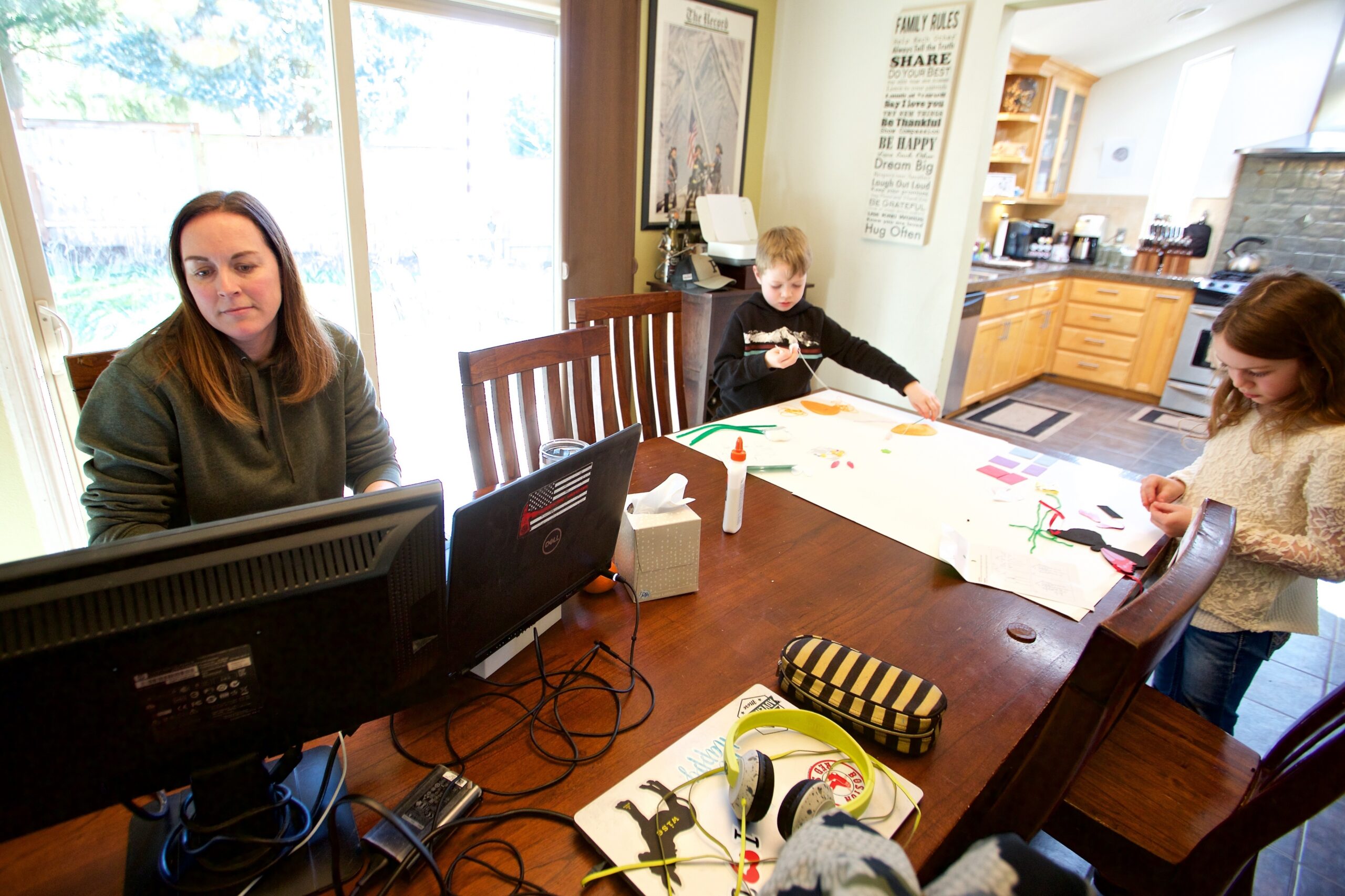 In this Tuesday, March 17, 2020 photo Kim Borton, left, works from home with her children