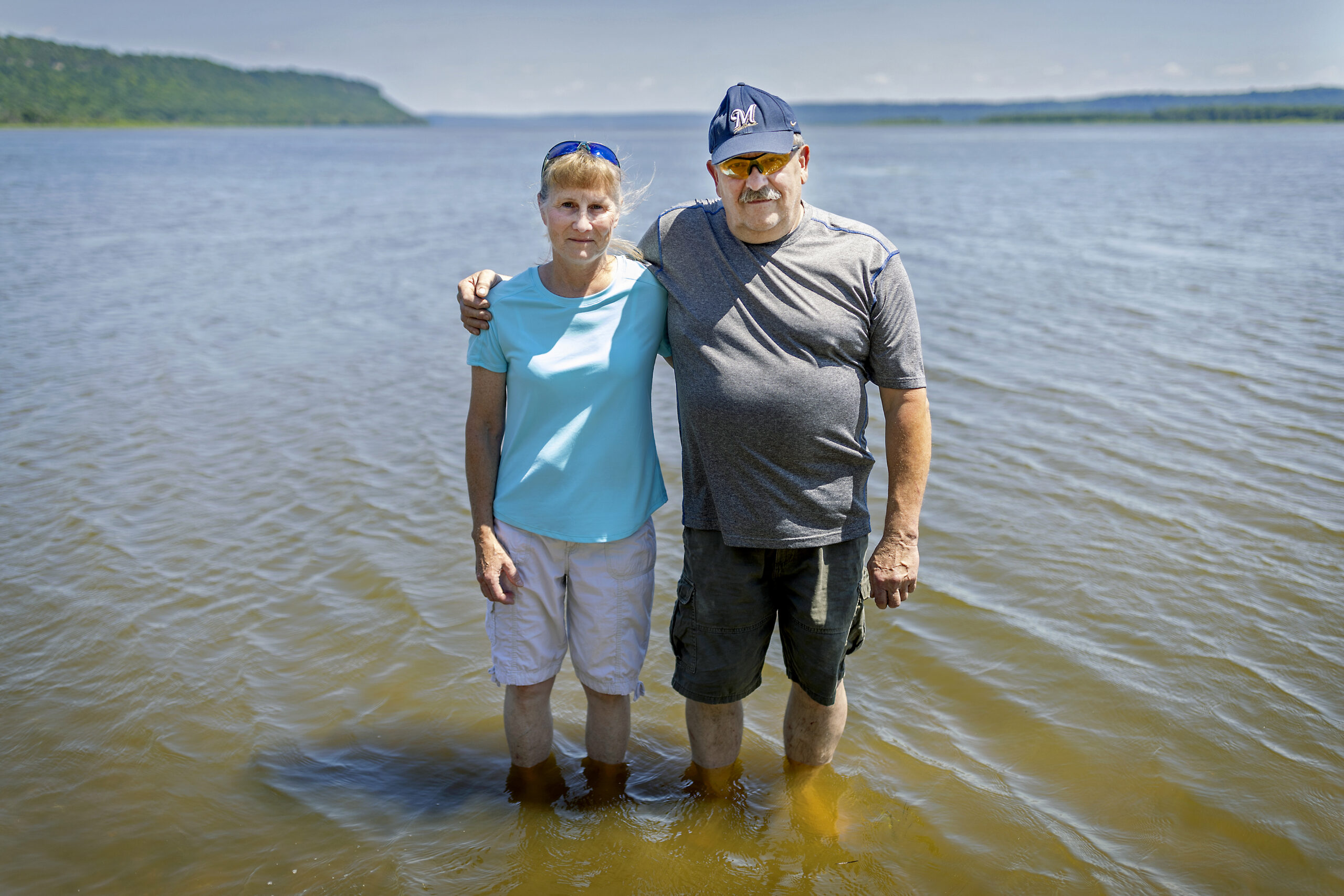 Frank and Cathy Dosdall stand in the water near a beach that should be filled with people in Bay City, a small Wisconsin town about an hour southeast of the Twin Cities