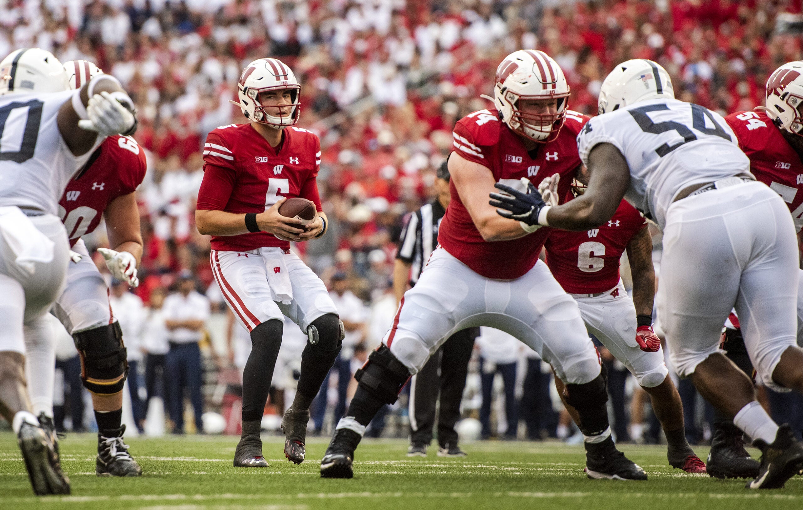 The quarterback steps back while holding the ball before deciding what to do.