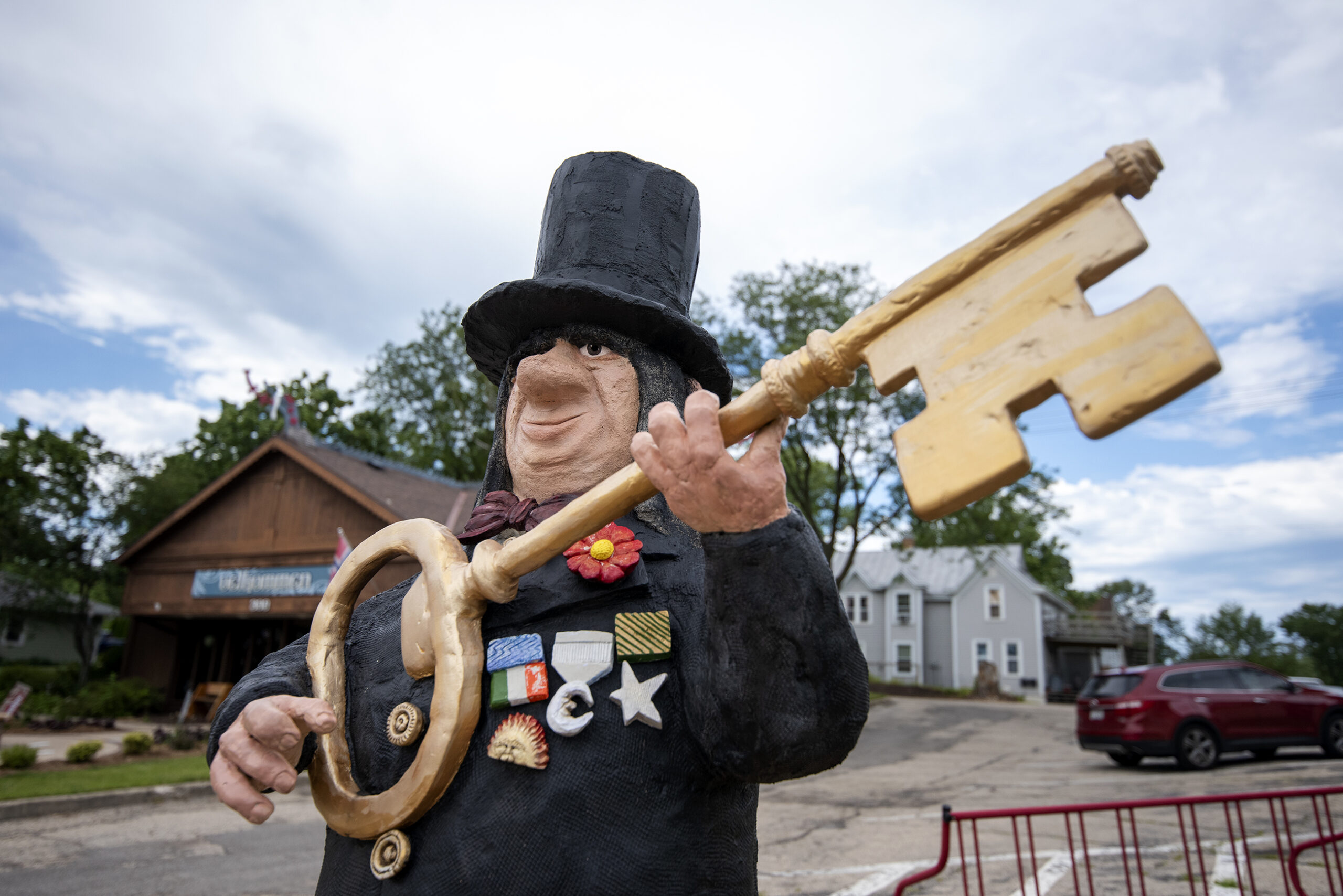 A statue shows a troll in a top hat holding a large golden key.