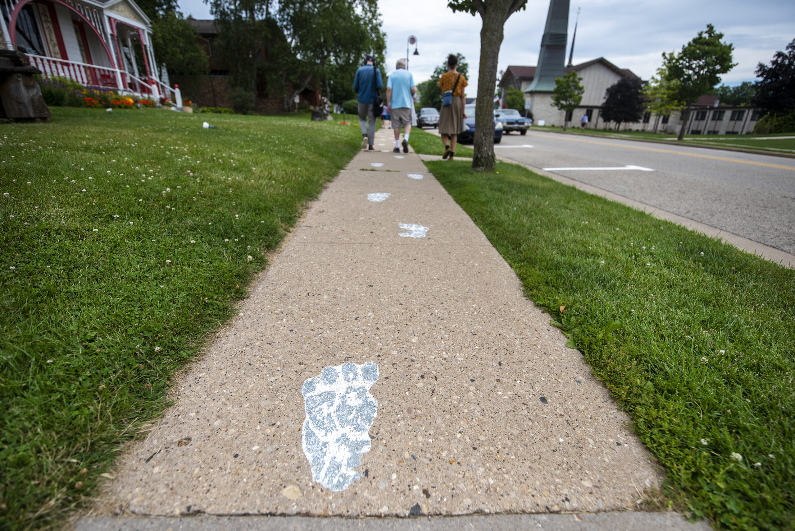 Gray foot prints are painted on a sidewalk.