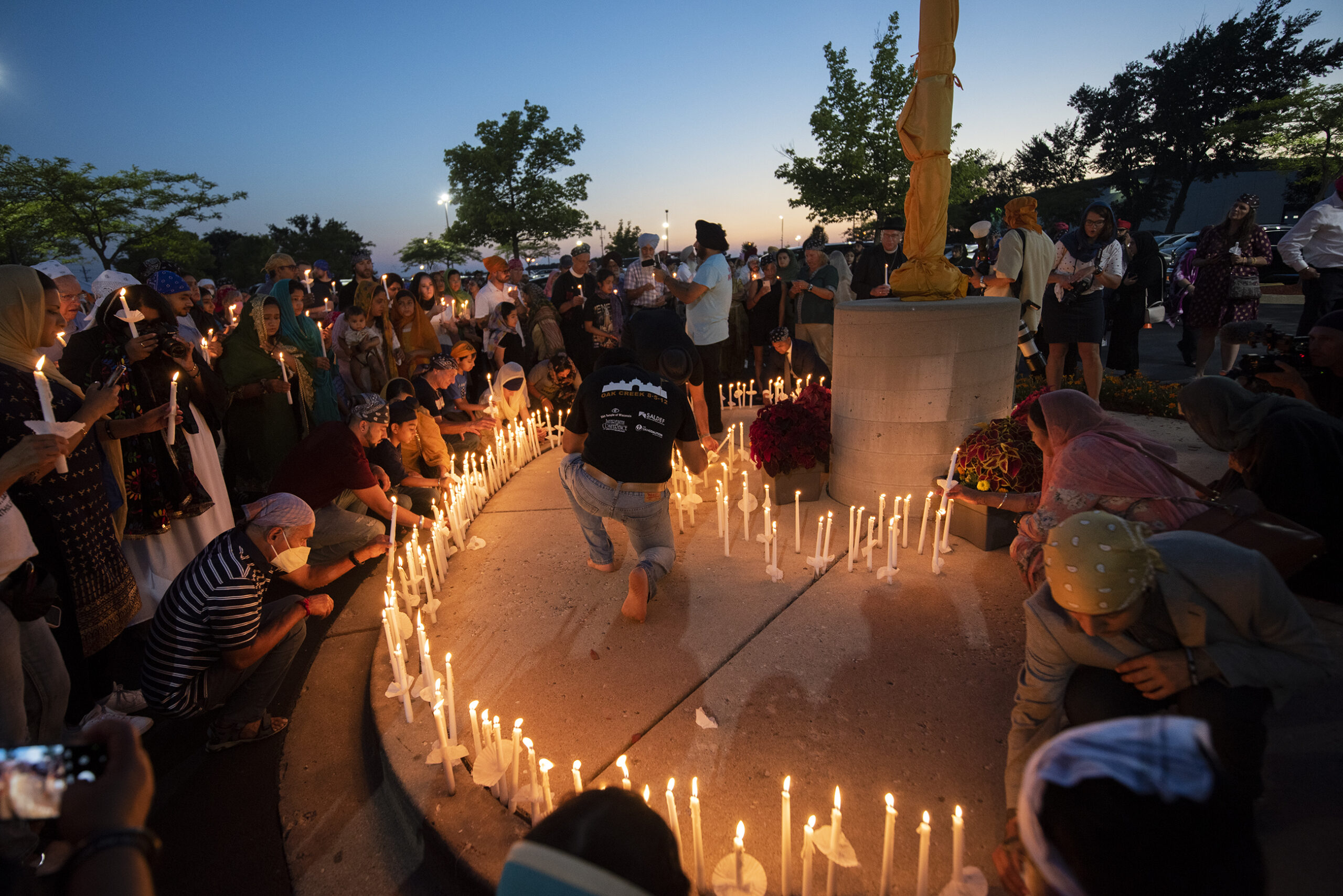 Candles are placed in a circle as people gather around.