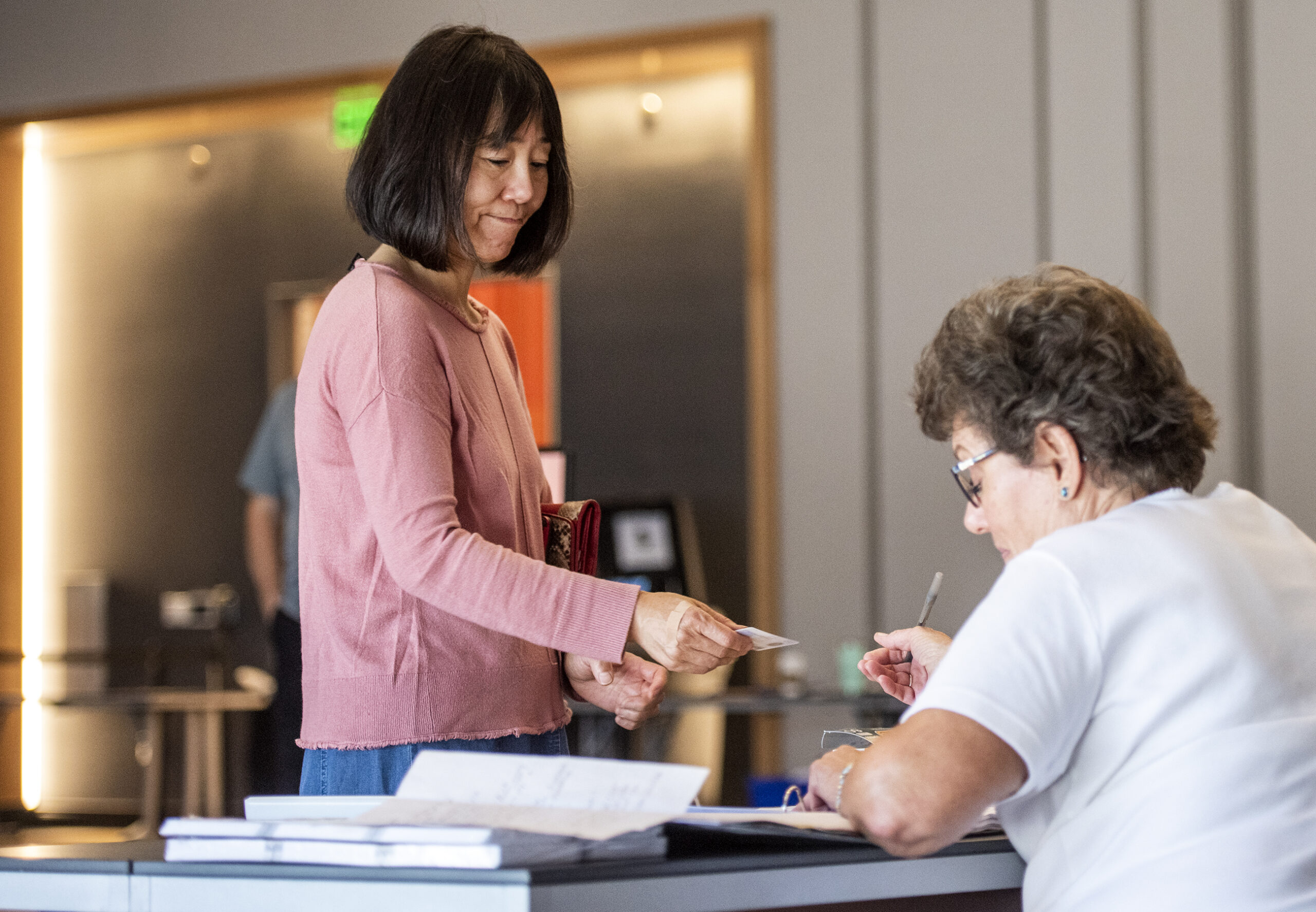 A woman stands at a table as she prepares to vote.