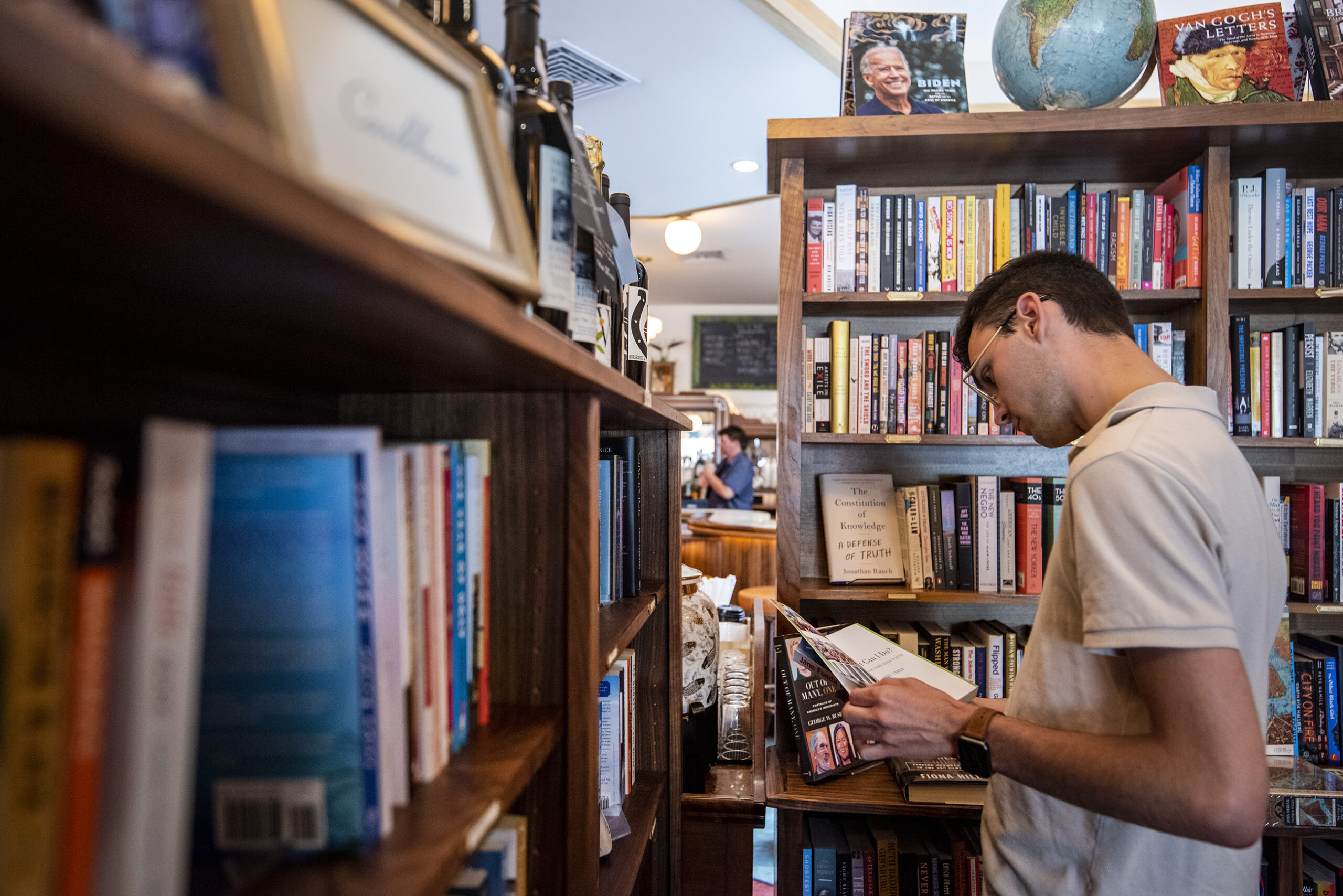A customer opens a book to look at it while surrounded by books on shelves.