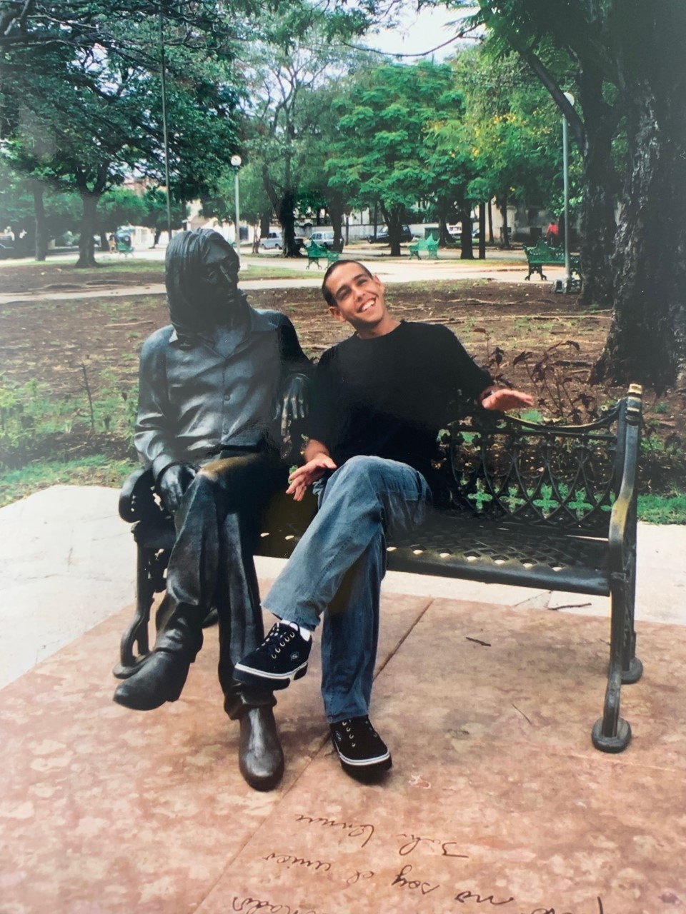 Omar Granados poses next to the John Lennon statue in Havana, Cuba