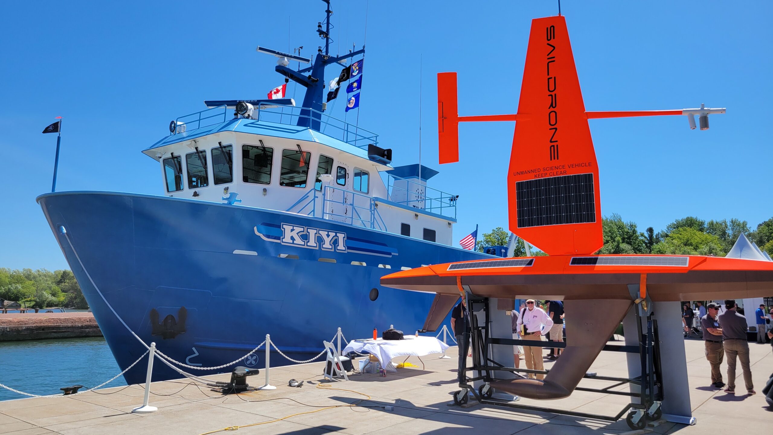 A sail drone stands on a dock next to the USGS research vessel Kiyi.