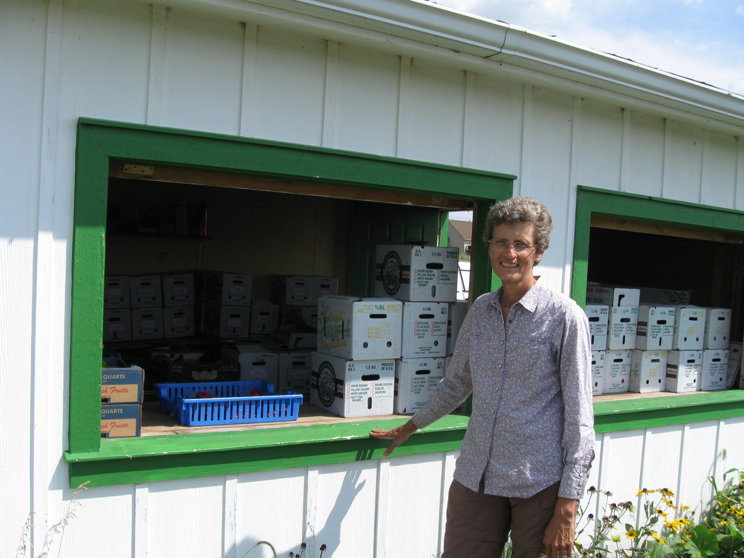 Angela Tedesco standing in front of building stacked with CSA boxes