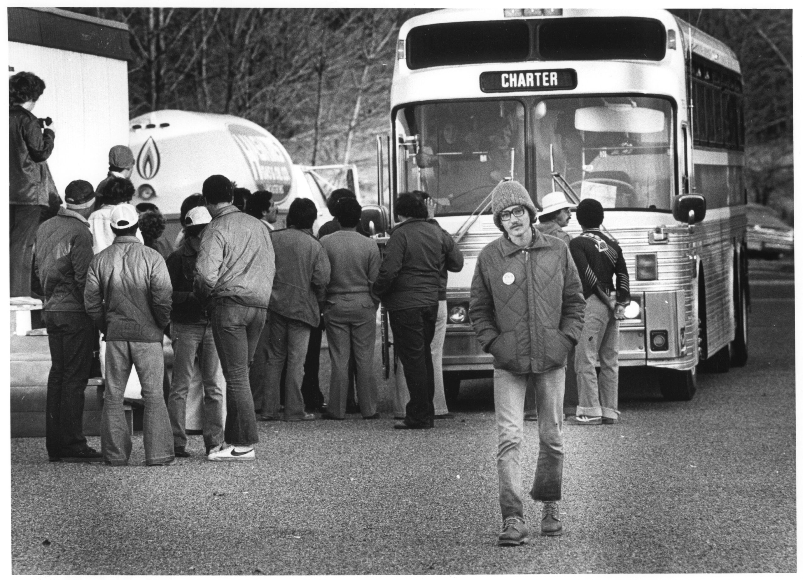 A black and white photograph featuring unidentified refugees gathered near a bus