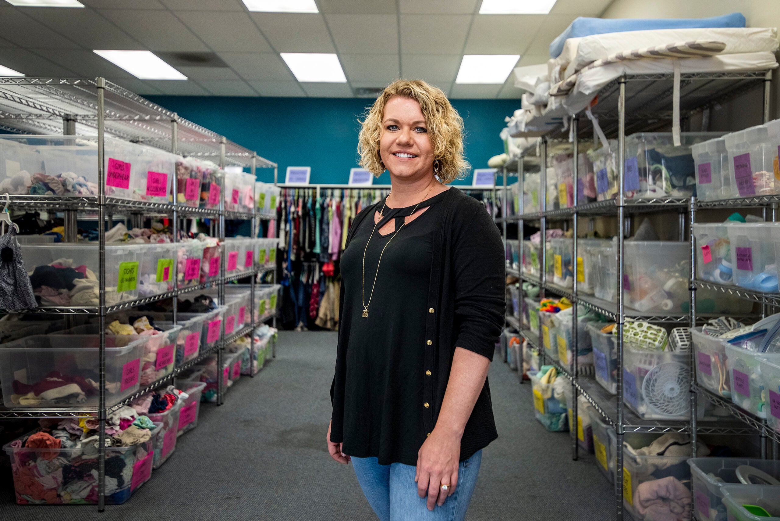A woman stands in a room filled with baby supplies.