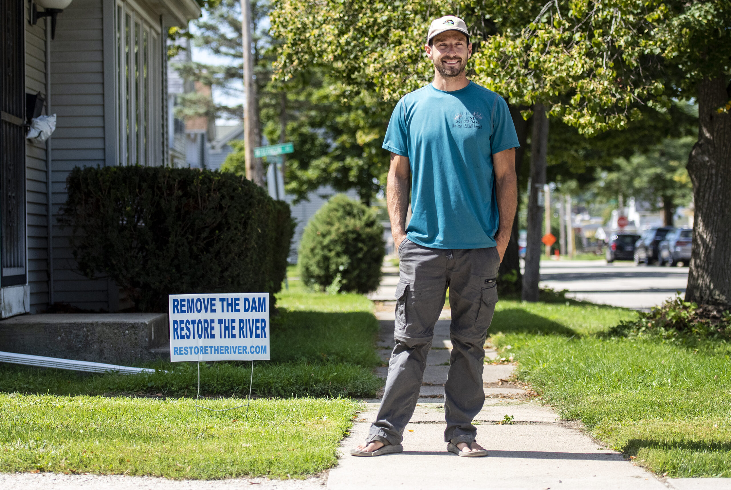 A man stands near a yard sign that says 