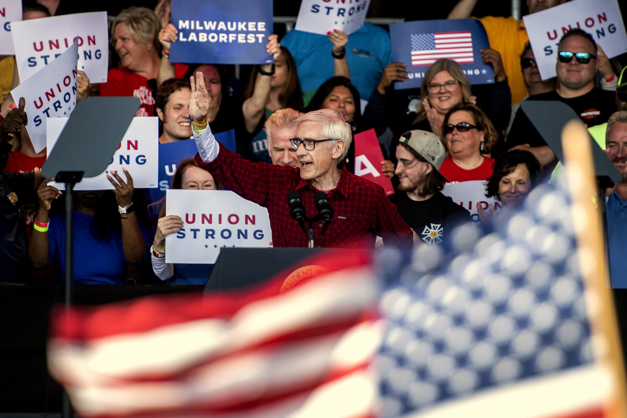 A U.S. flag flies in front of Gov. Tony Evers as he approaches the podium.