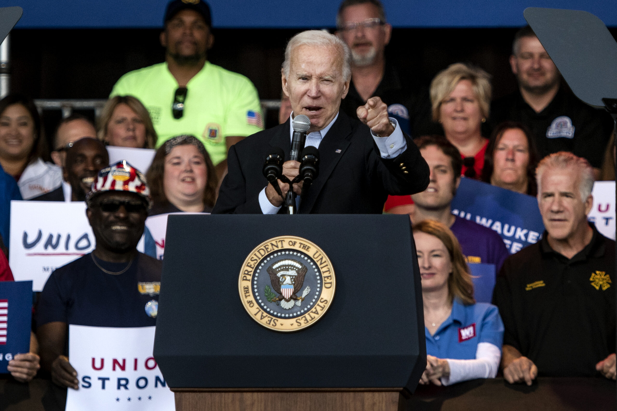 Pres. Joe Biden points at the crowd as he speaks at a podium.