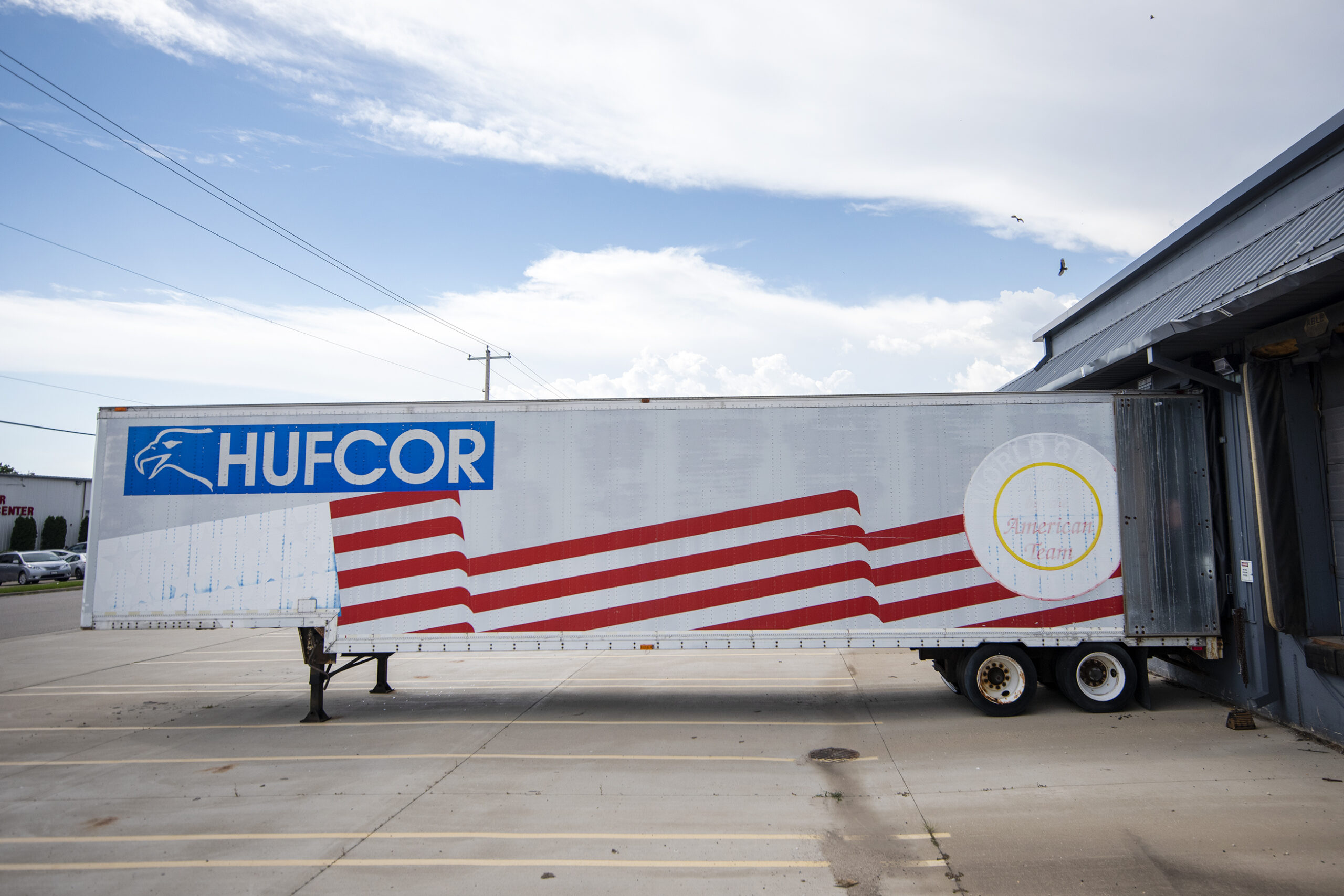 A trailer with red stripes says "HUFCOR" on the side.