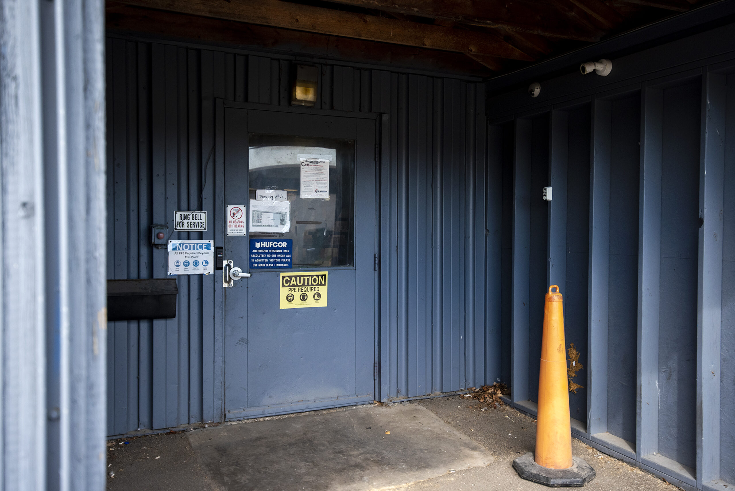 A navy blue doorway has signs and a cone outside of it.