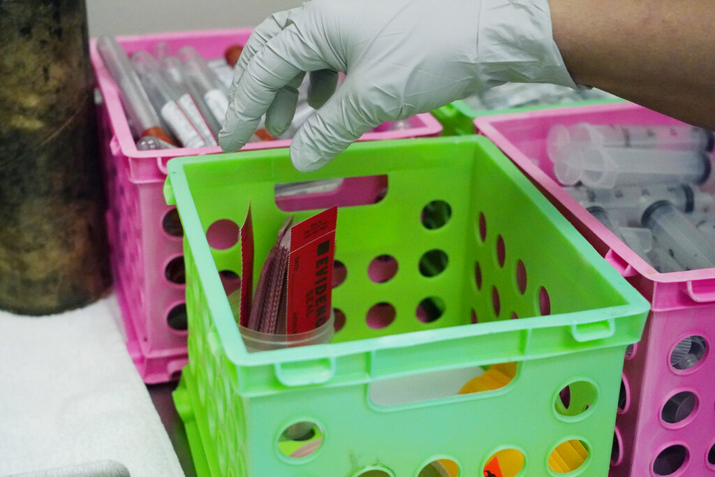 A forensic pathologist reaches for an evidence seal