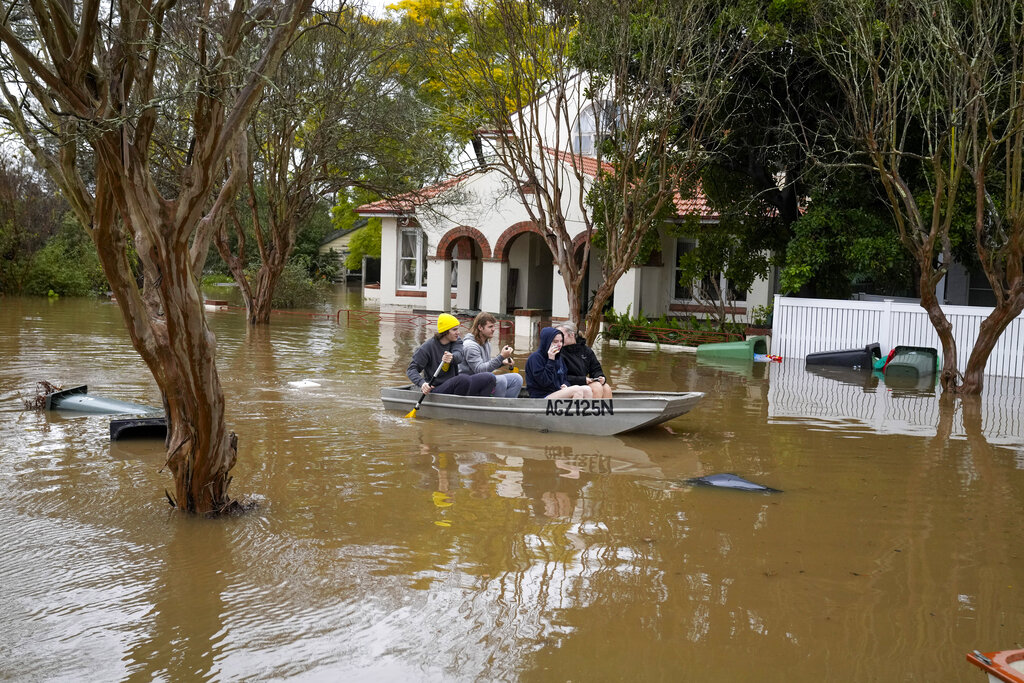 People paddle a boat through a flooded street