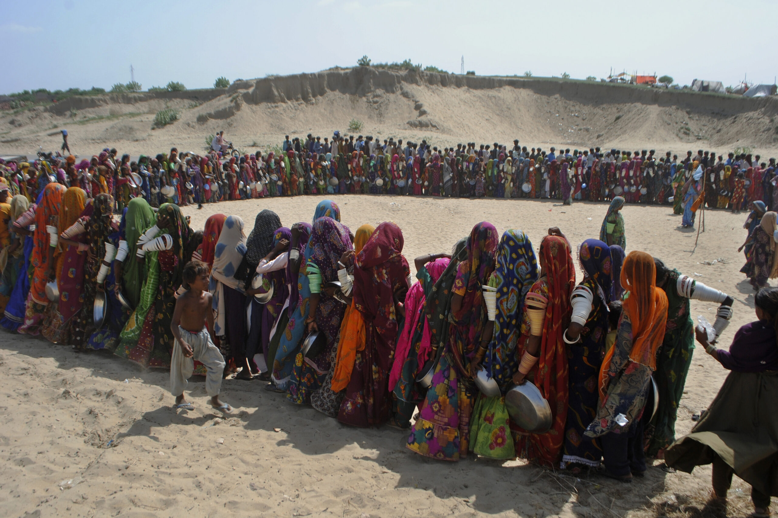 People from flood-affected areas wait to get free food distributed by a charity