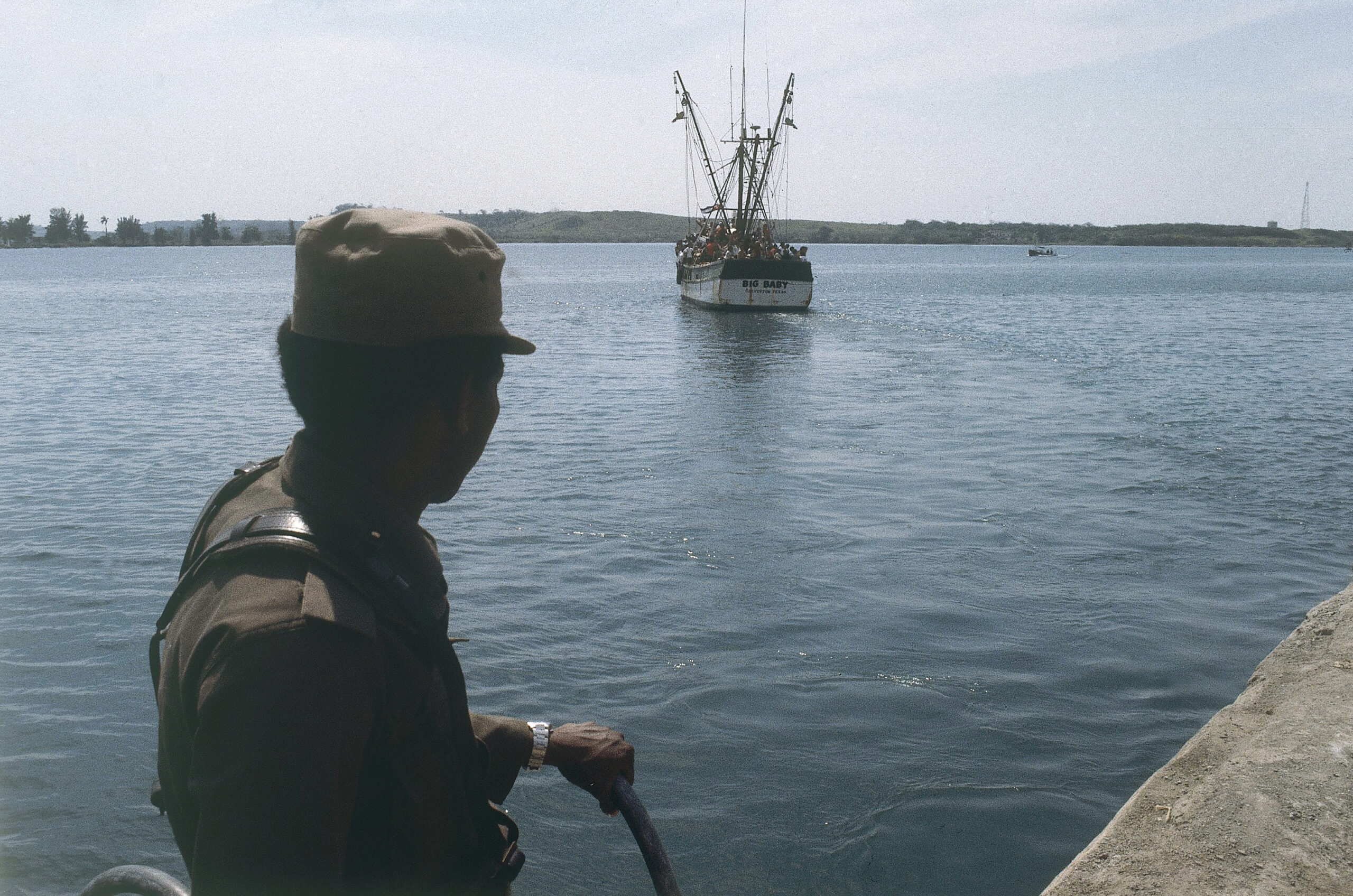 A Cuban soldier looks after a refugee ship at the small port of Mariel, Cuba in 1980 as refugees aboard sail for U.S.