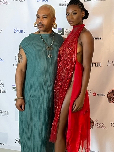 A fashion school student poses with a model wearing one of his designs, a red dress