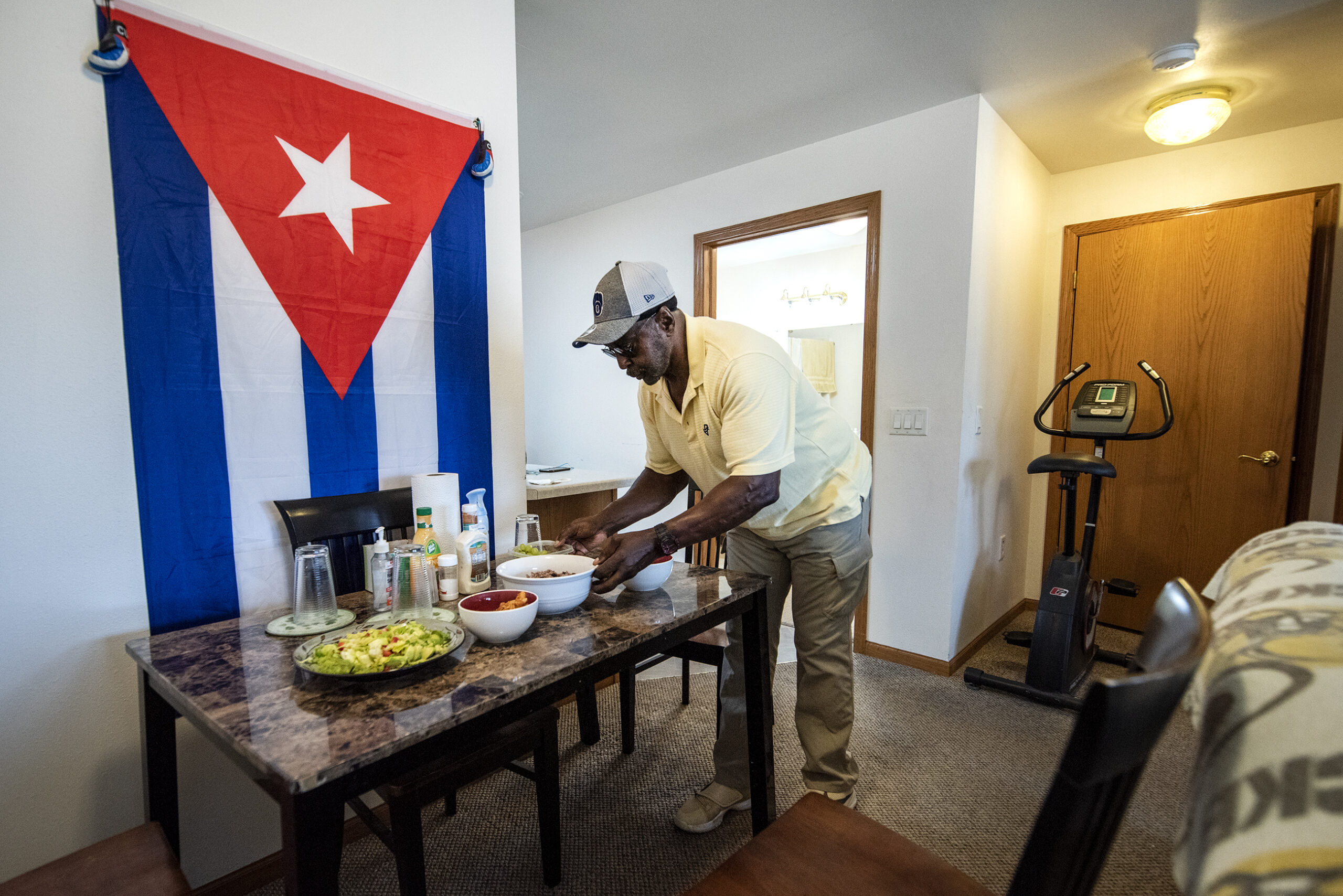 Osvaldo Durruthy prepares congri on his dining table. A large Cuban flag is hung over the table