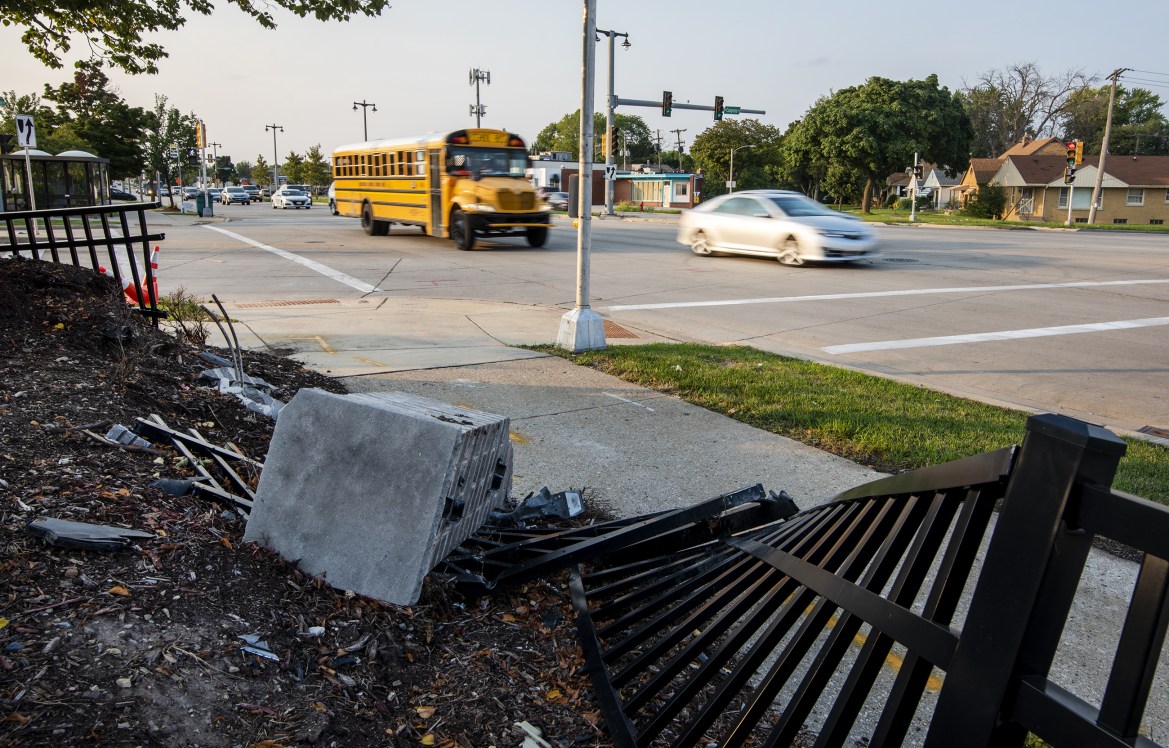 Vehicles drive past a fence that was damaged during a crash on West Fond du Lac Avenue and West Congress Street in Milwaukee