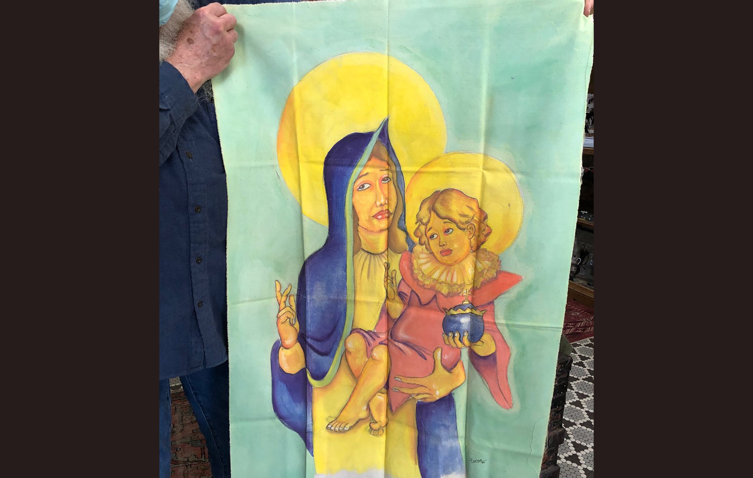 John Satory holds art created on a bedsheet of la Virgen de la Caridad del Cobre.