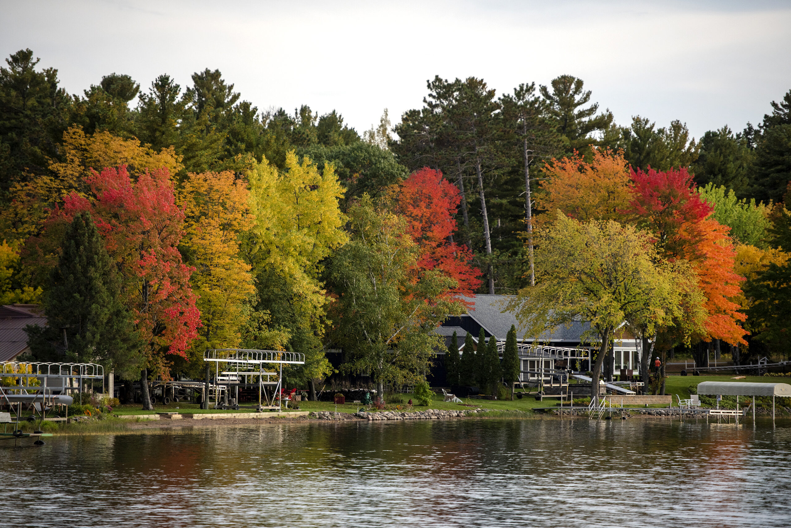 Bright red, orange, and yellow leaves surround homes on a lake.