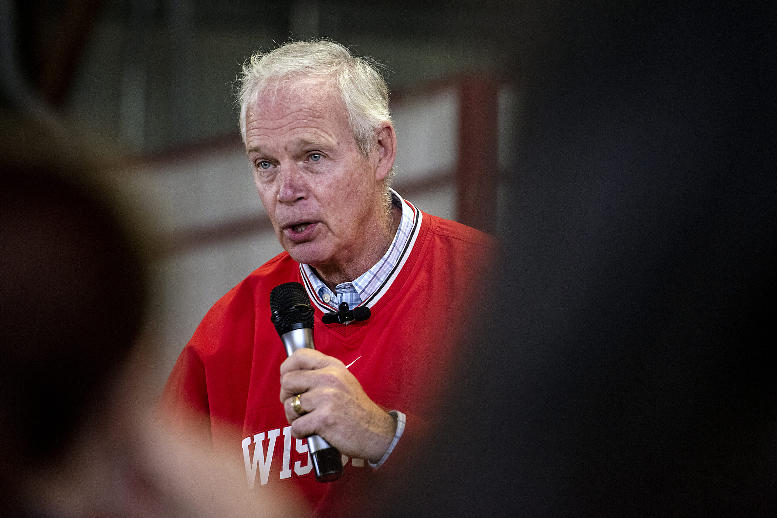 Sen. Ron Johnson is seen in between people sitting in a crowd as he speaks.