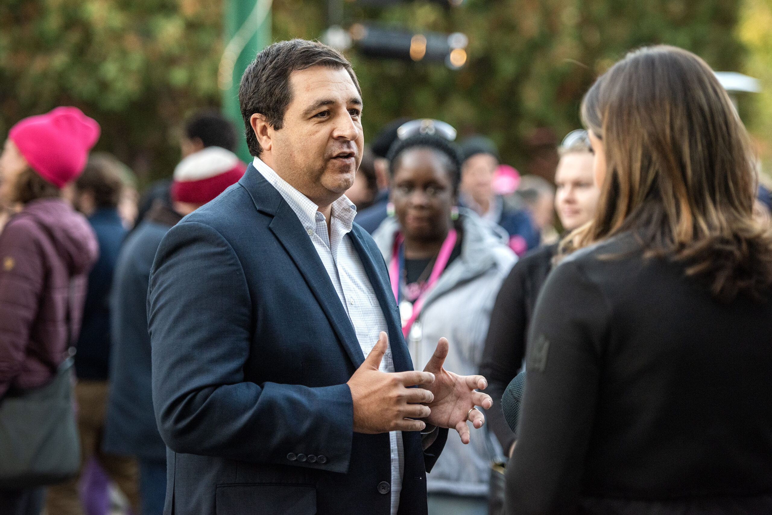 Attorney General Josh Kaul stands outside near a group of reporters.