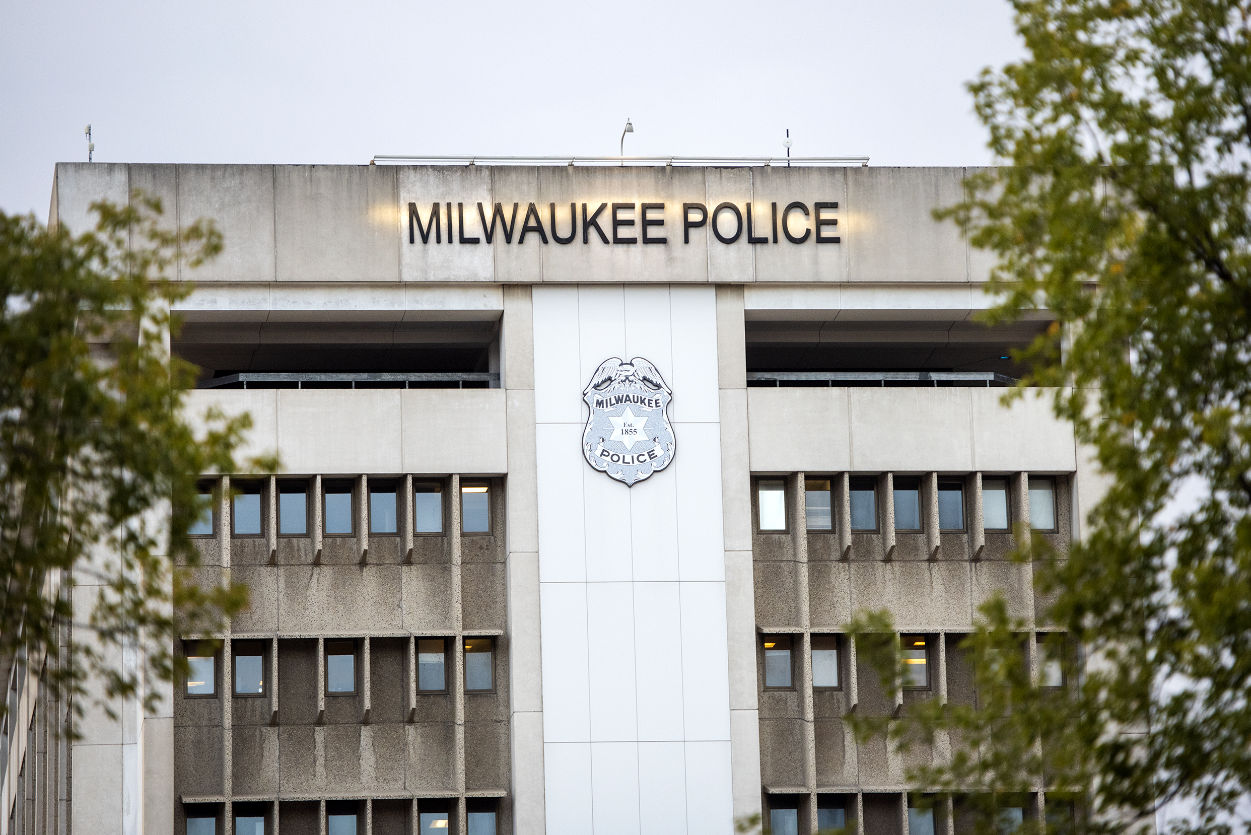 Trees surround a tall building that says "Milwaukee Police"