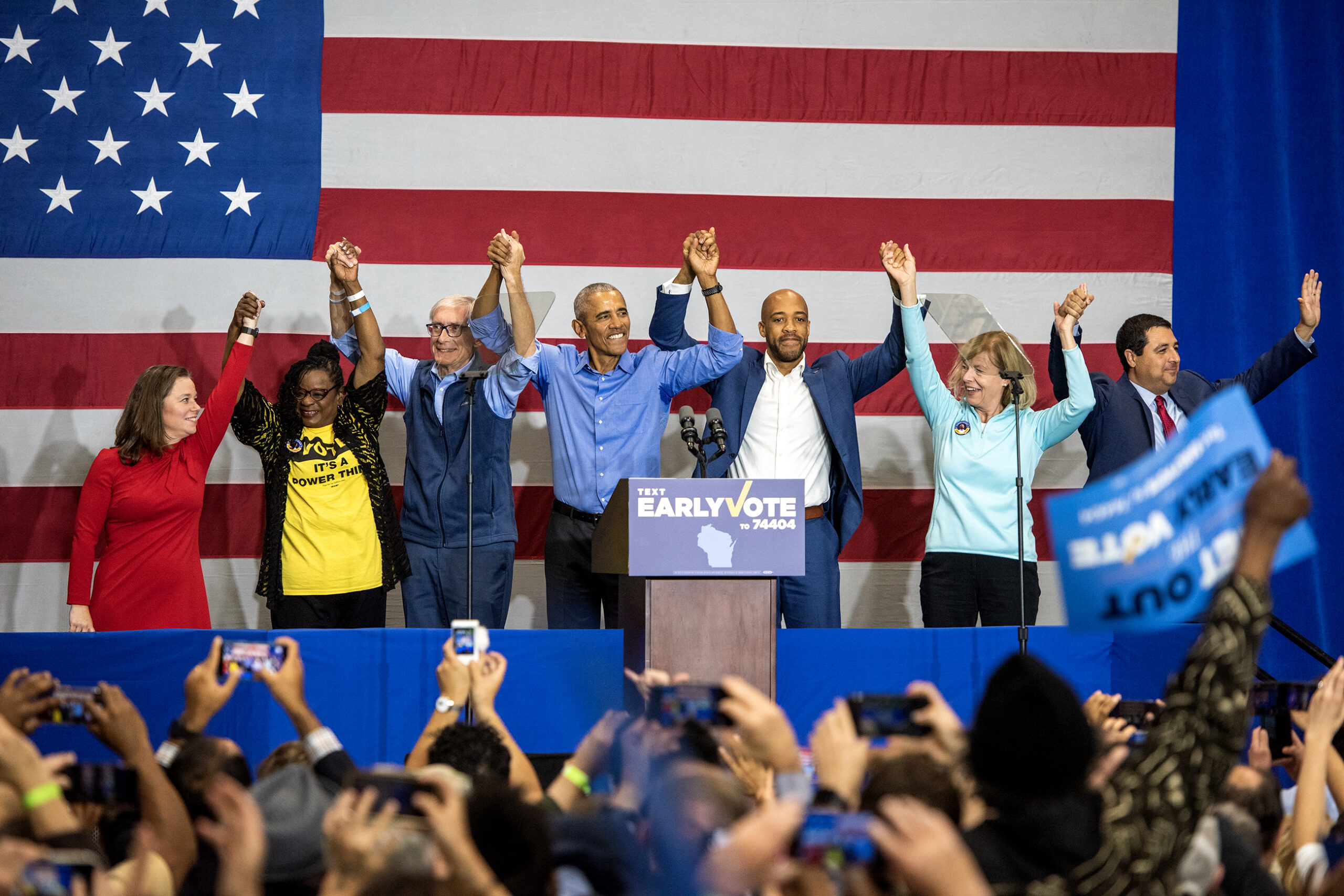 Former President Barack Obama joins hands on stage with Democratic candidates for office.