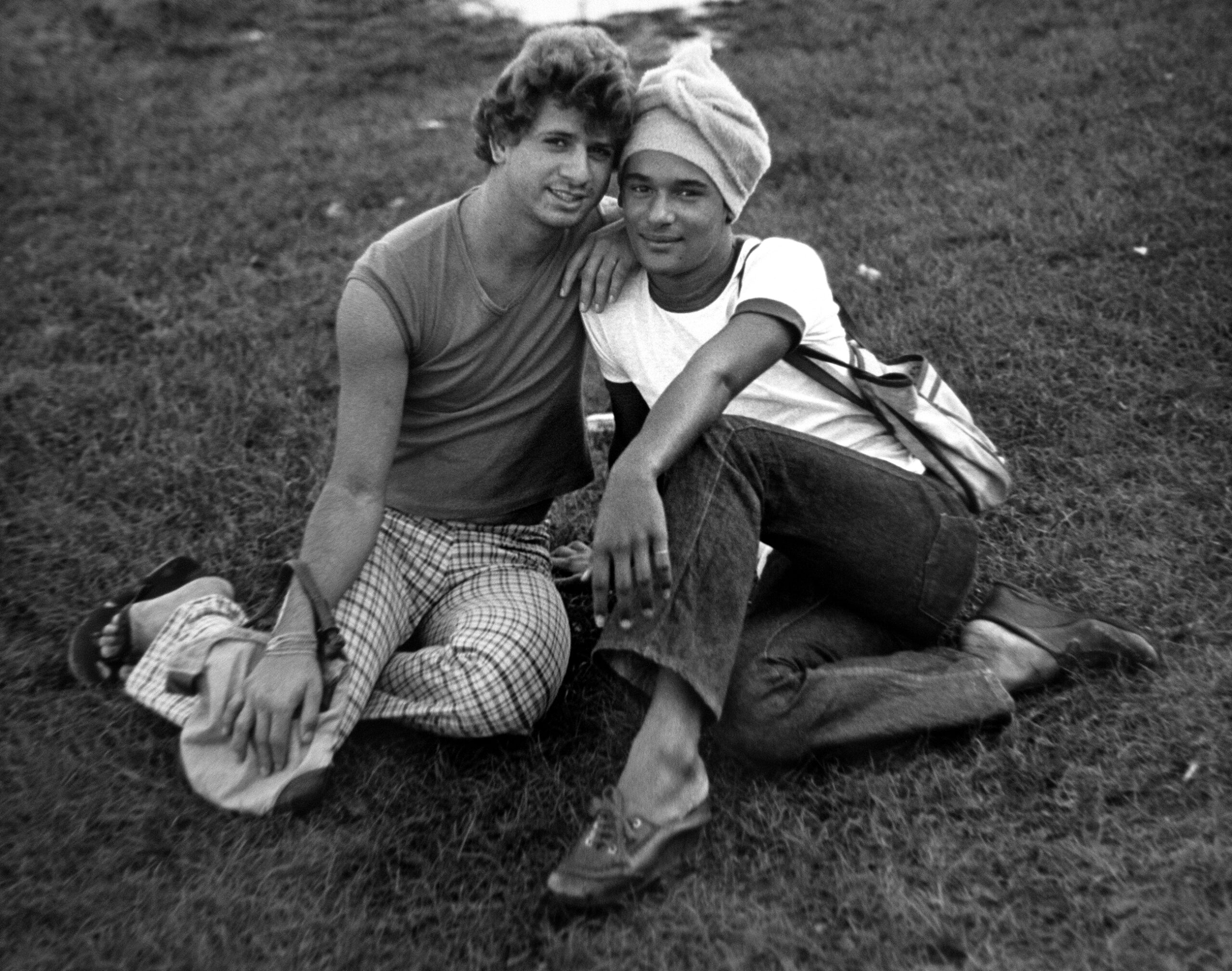 Two Cuban refugees pose, sitting on the grass