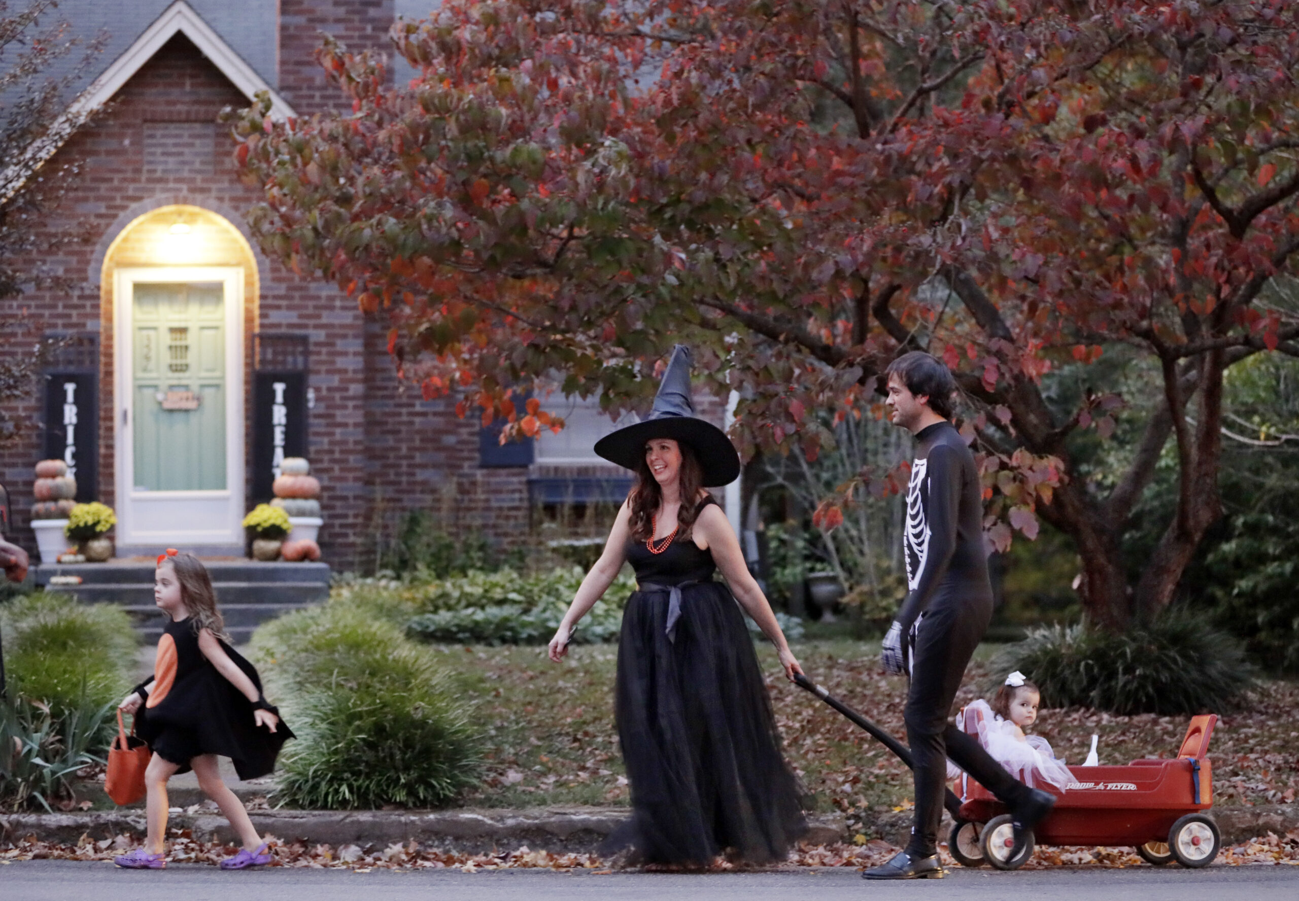 Three people go trick or treating in costumes.