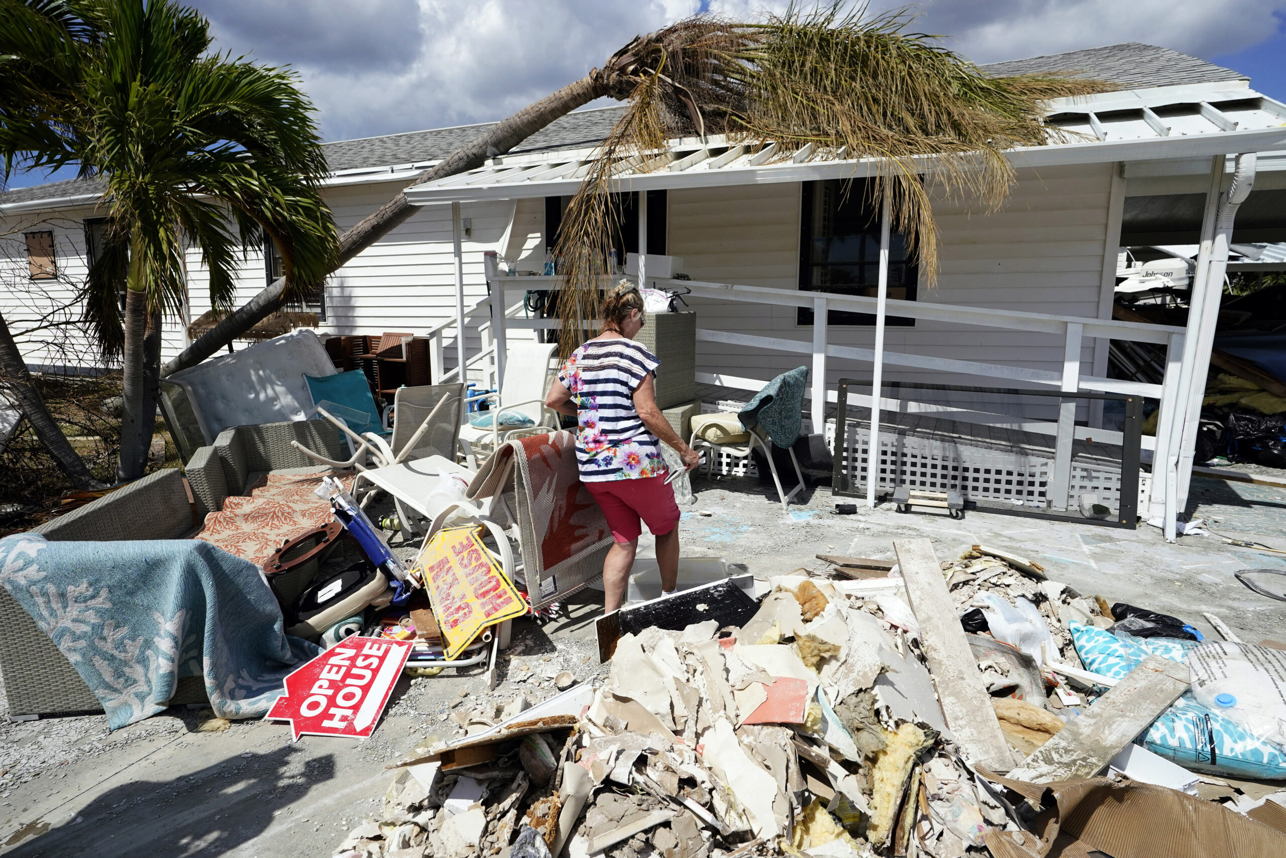 A woman walks toward her hurricane-damaged mobile home