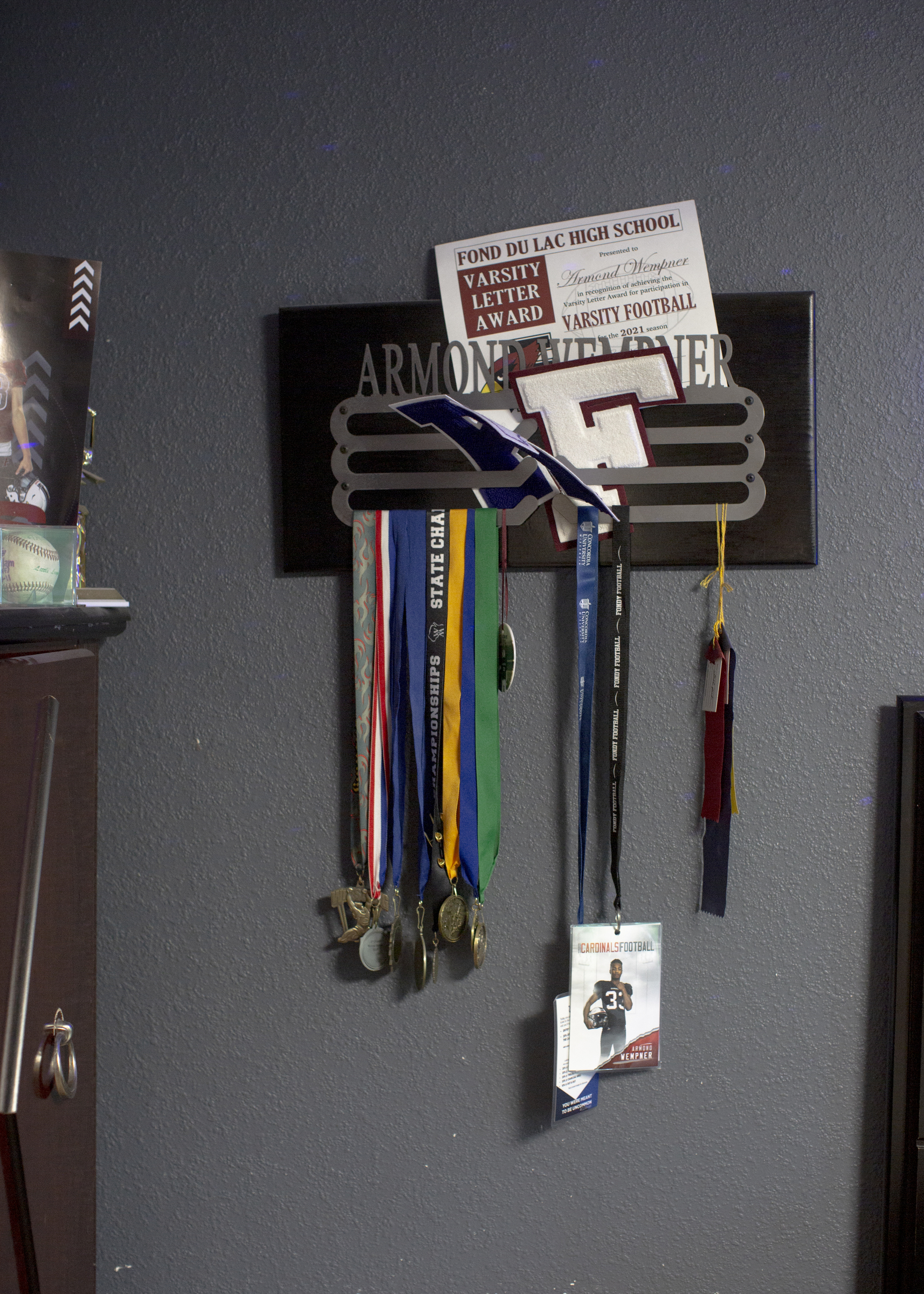Armond Wempner’s athletic awards and mementos are shown on a wall of his parents’ home outside of Kiel, Wis.