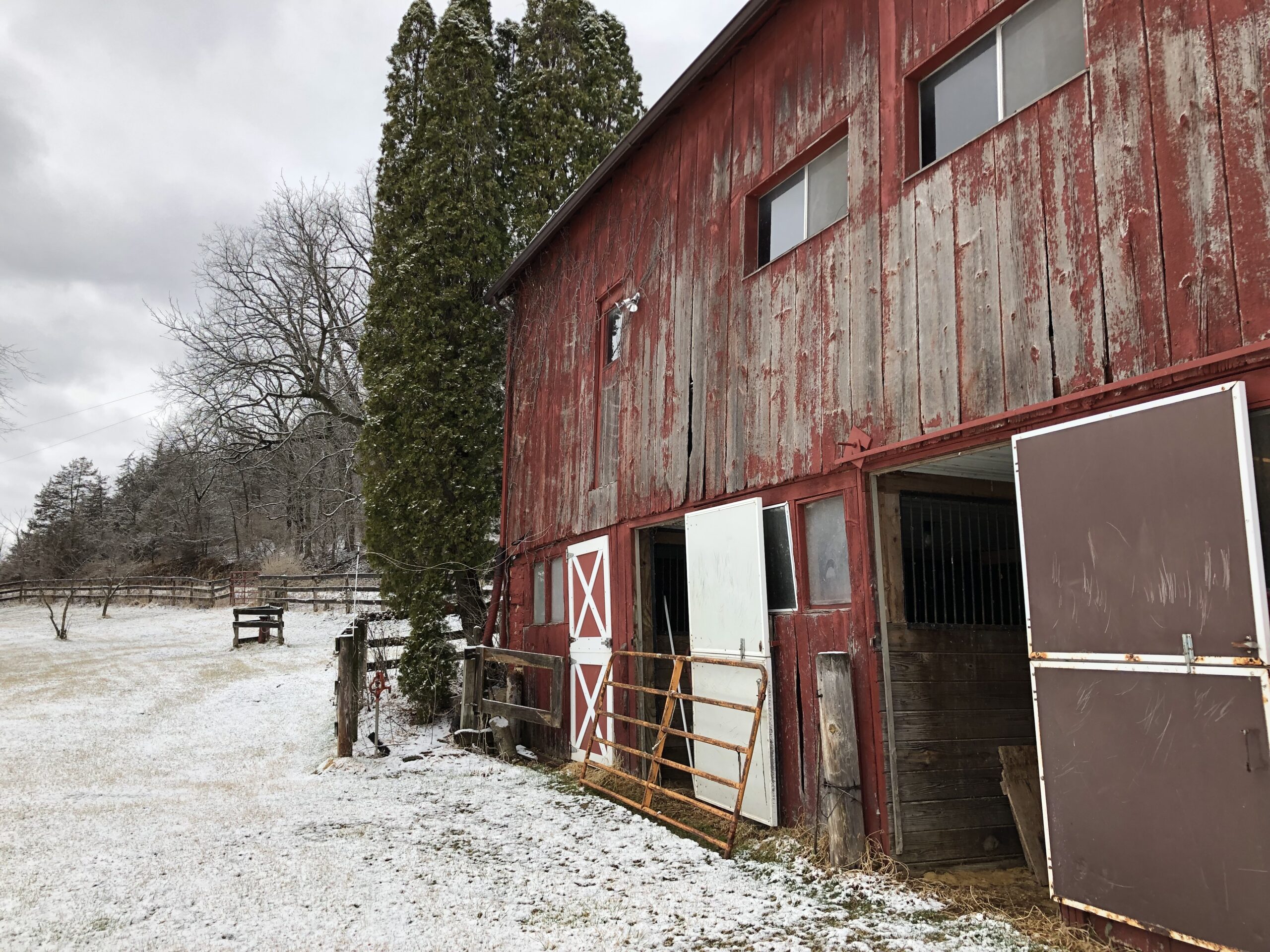 A red barn sits on a snowy yard.
