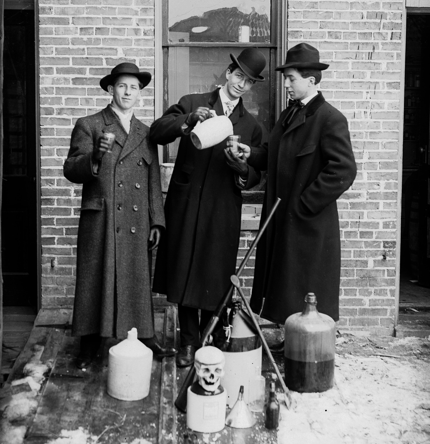 three men in long coats and hats are standing outdoors and staging an elaborate temperance portrait