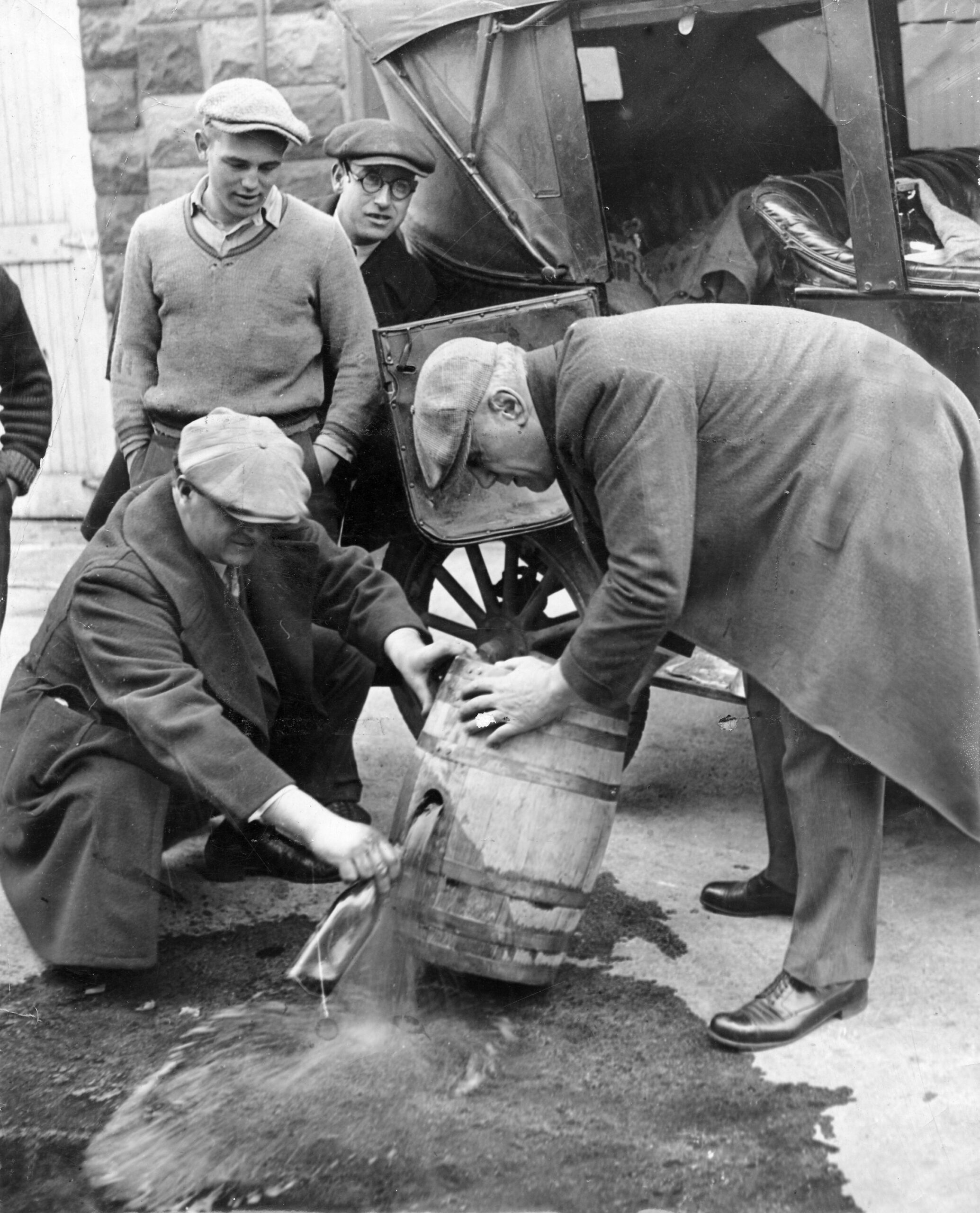 Prohibition agents empty a bootlegger's keg during an enforcement raid