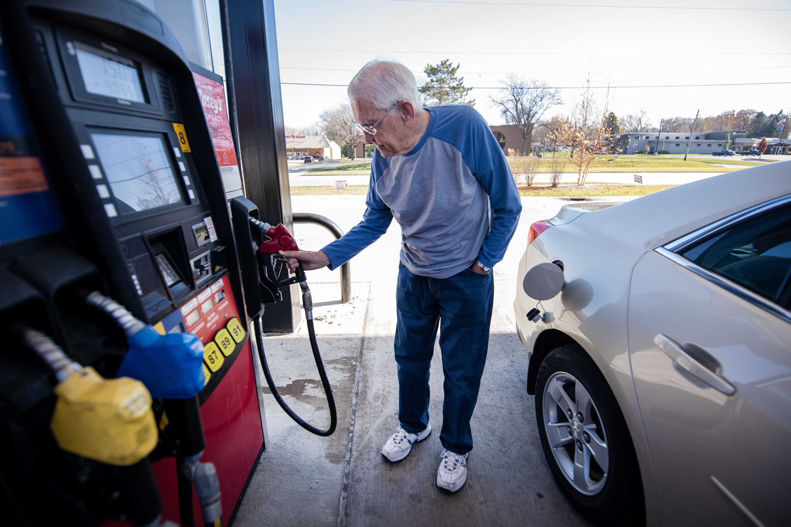 A man reaches to put the pump back after fueling up his car.