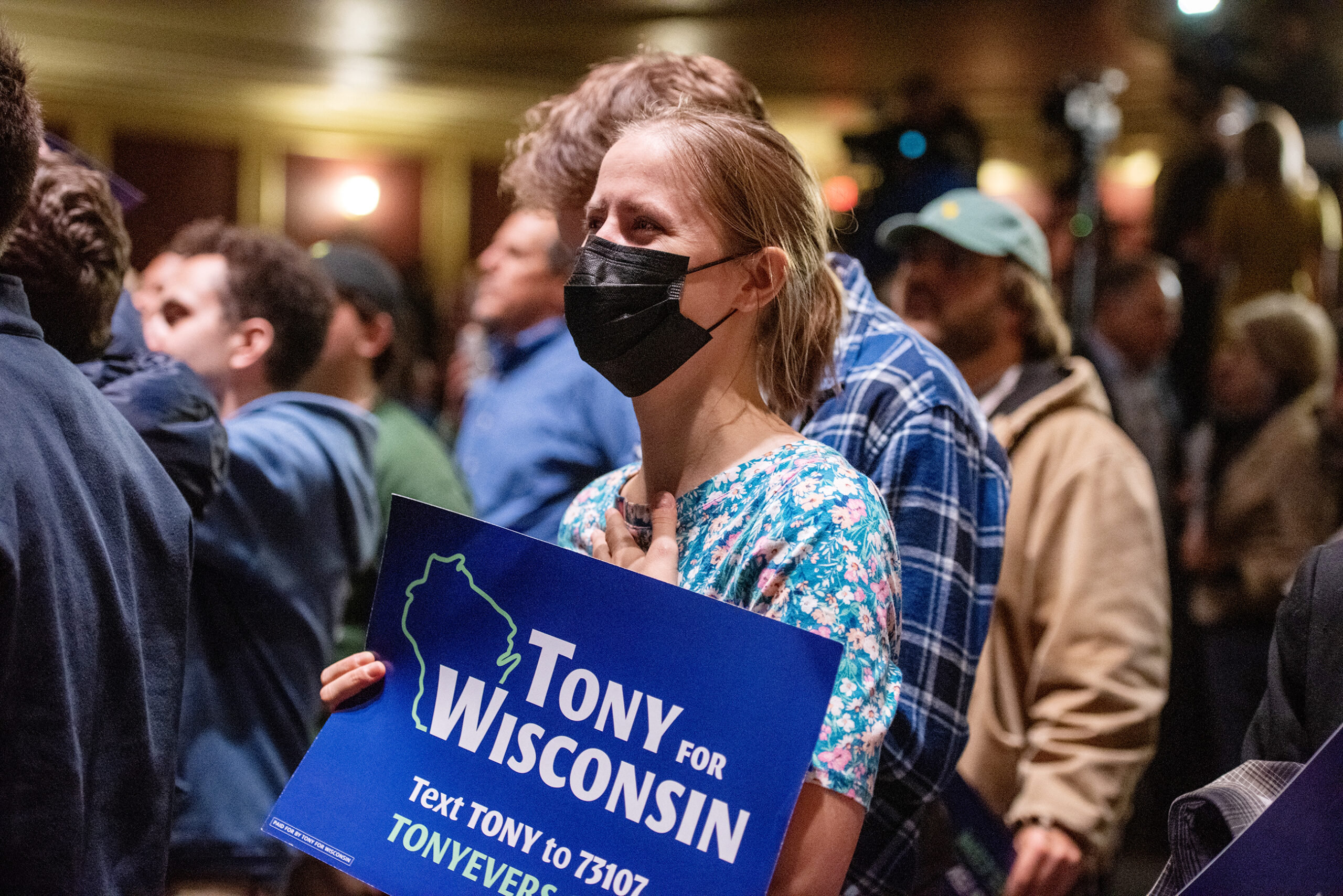A woman stands with a Tony for Wisconsin sign with a look of relief on her face.