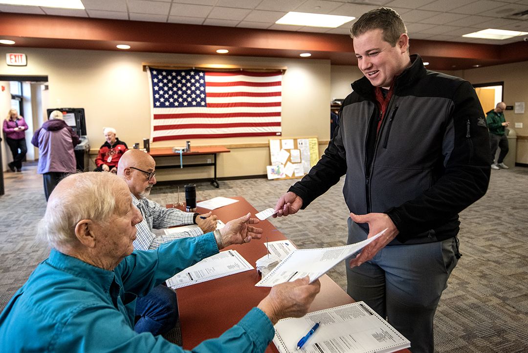 A voter smiles as he receives a ballot.