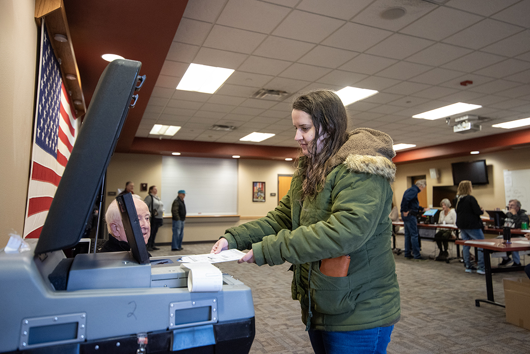 A voter puts her ballot into the machine.