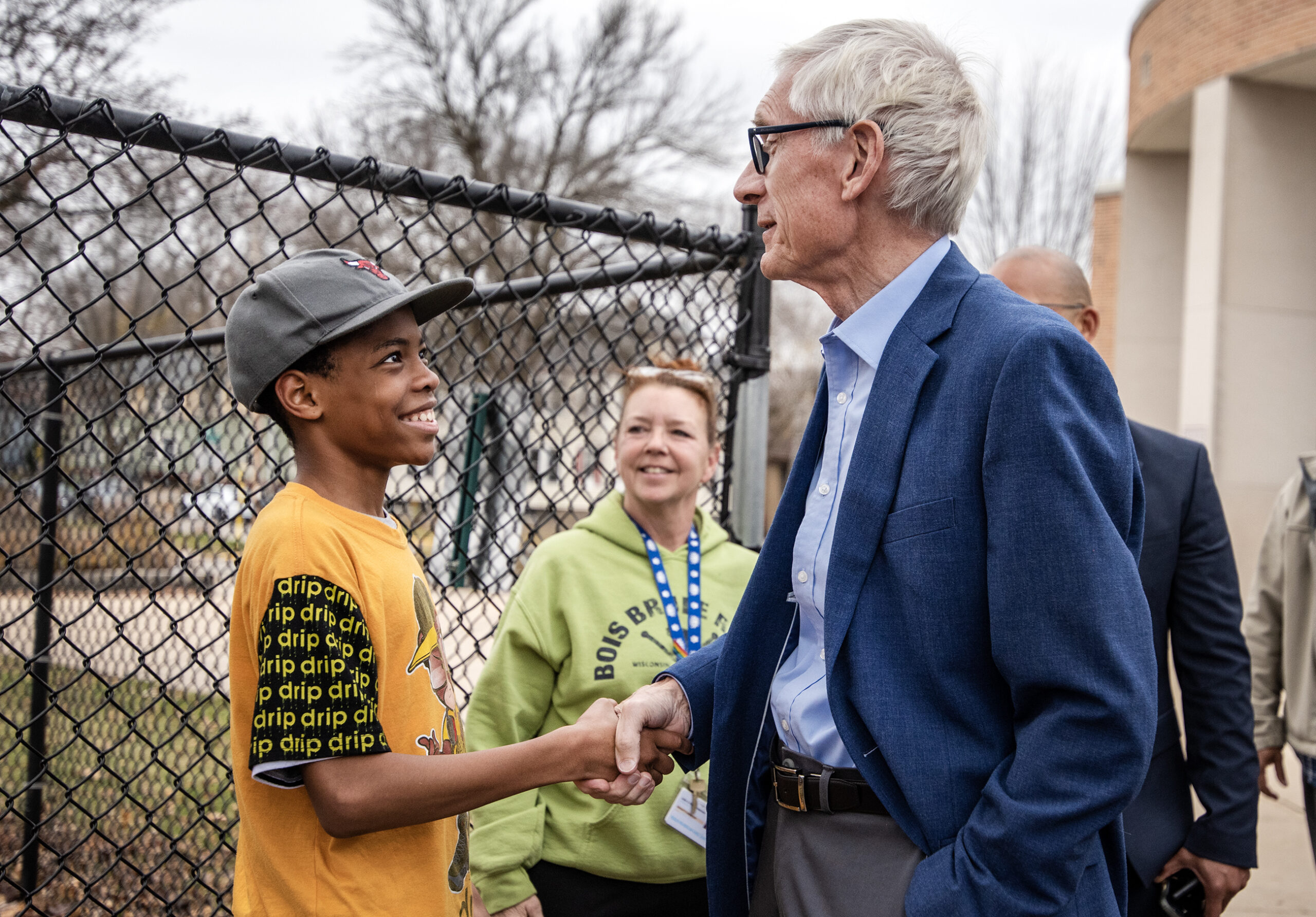 Gov. Evers shakes hands with a boy outside on a playground.