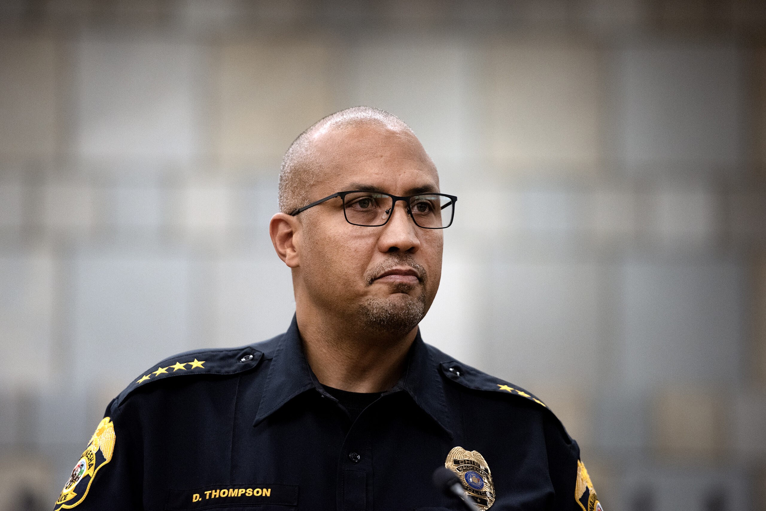 A man in police uniform looks out at reporters.