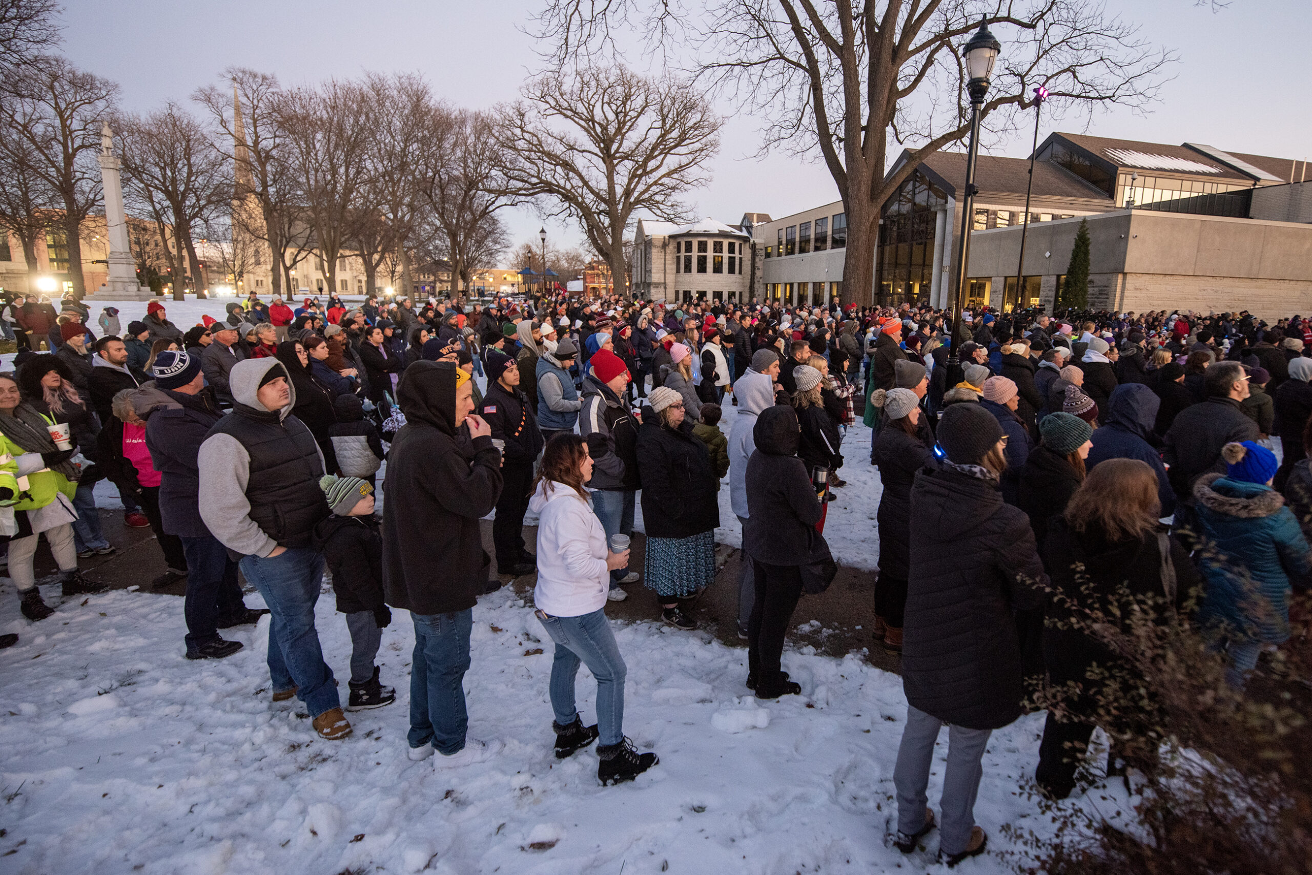 A crowd of people stand together in a park.