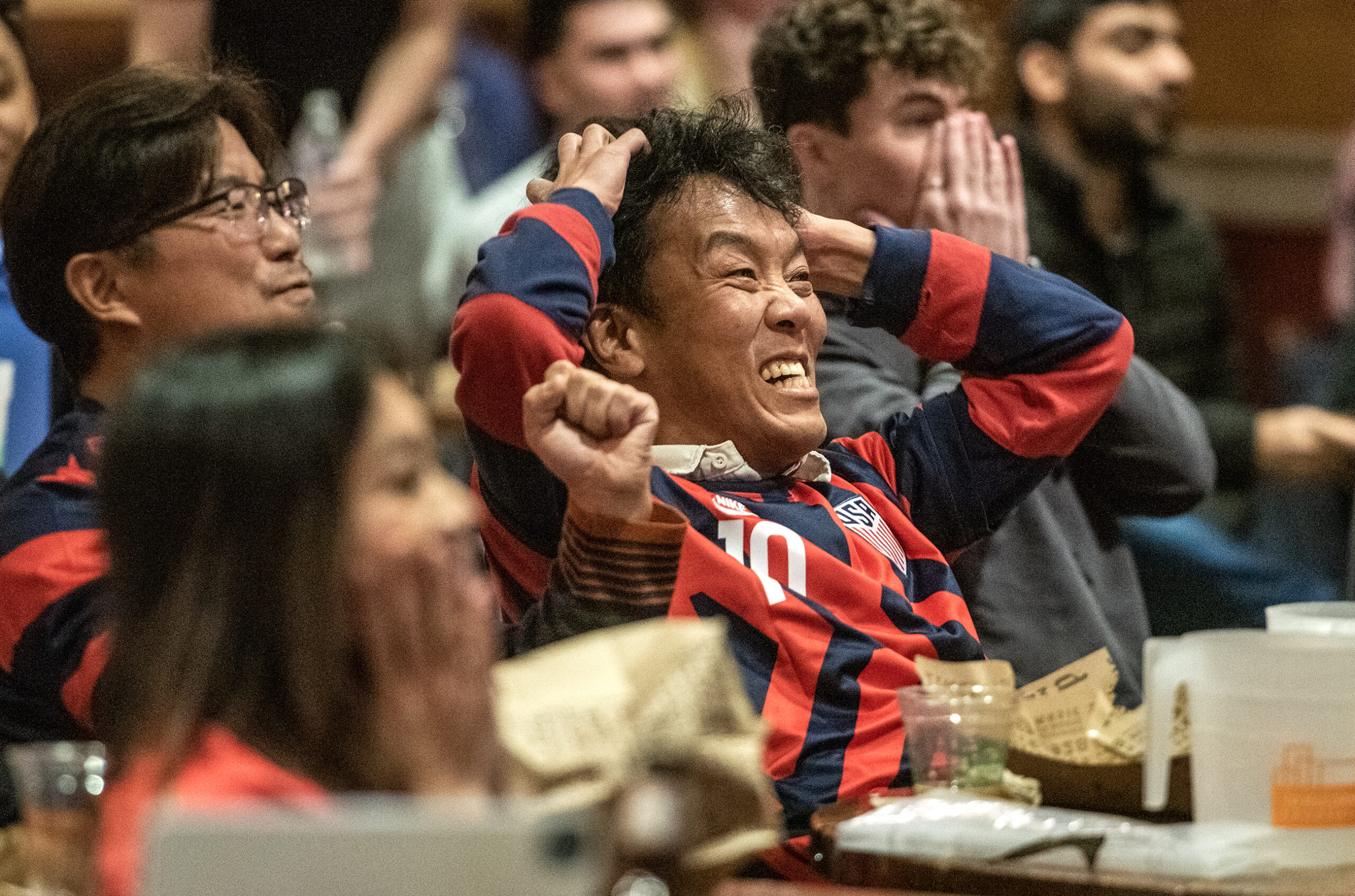 A fan in a USA shirt clutches his head and expresses frustration.