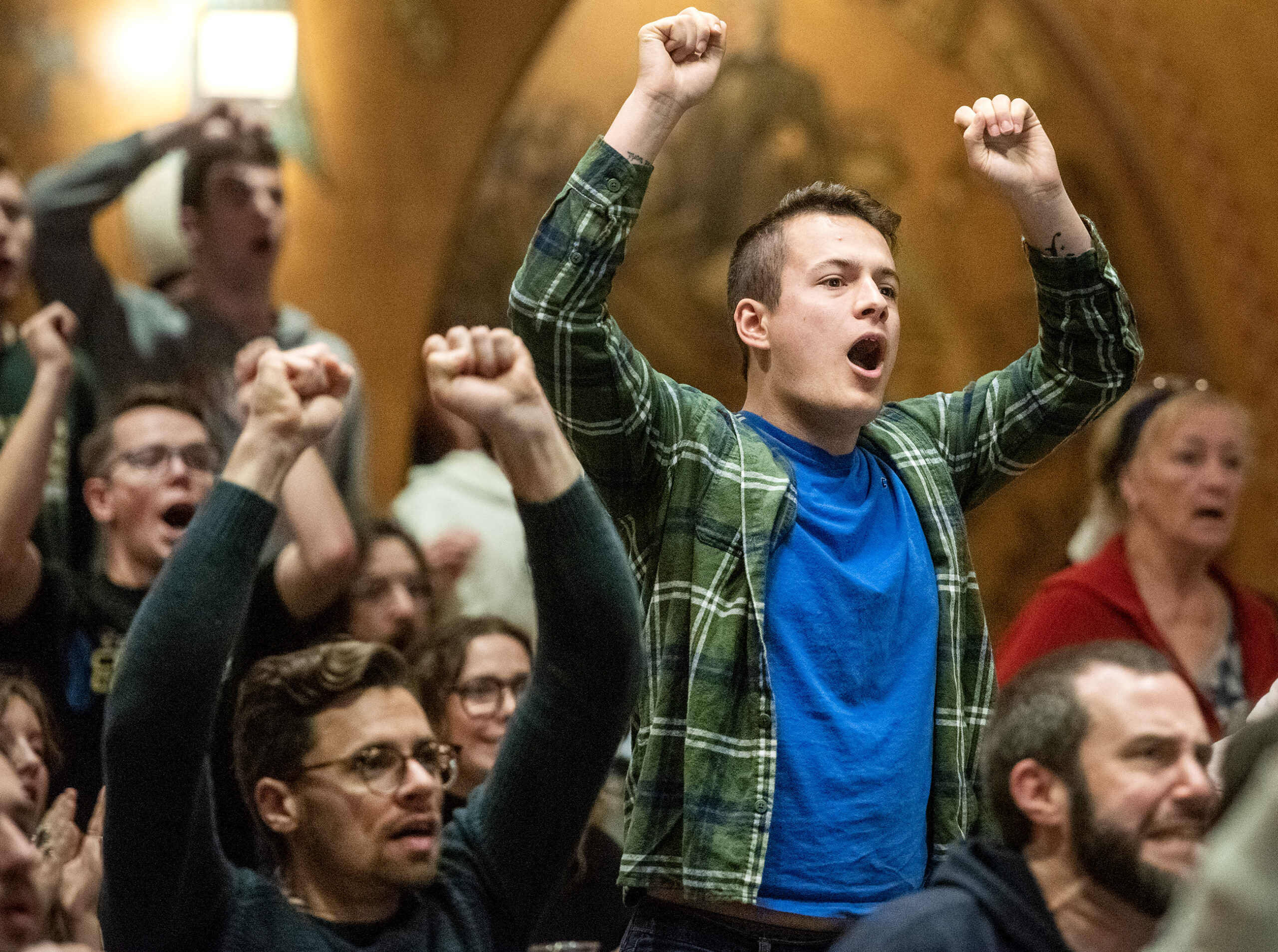 Fans celebrate by standing and raising their arms.